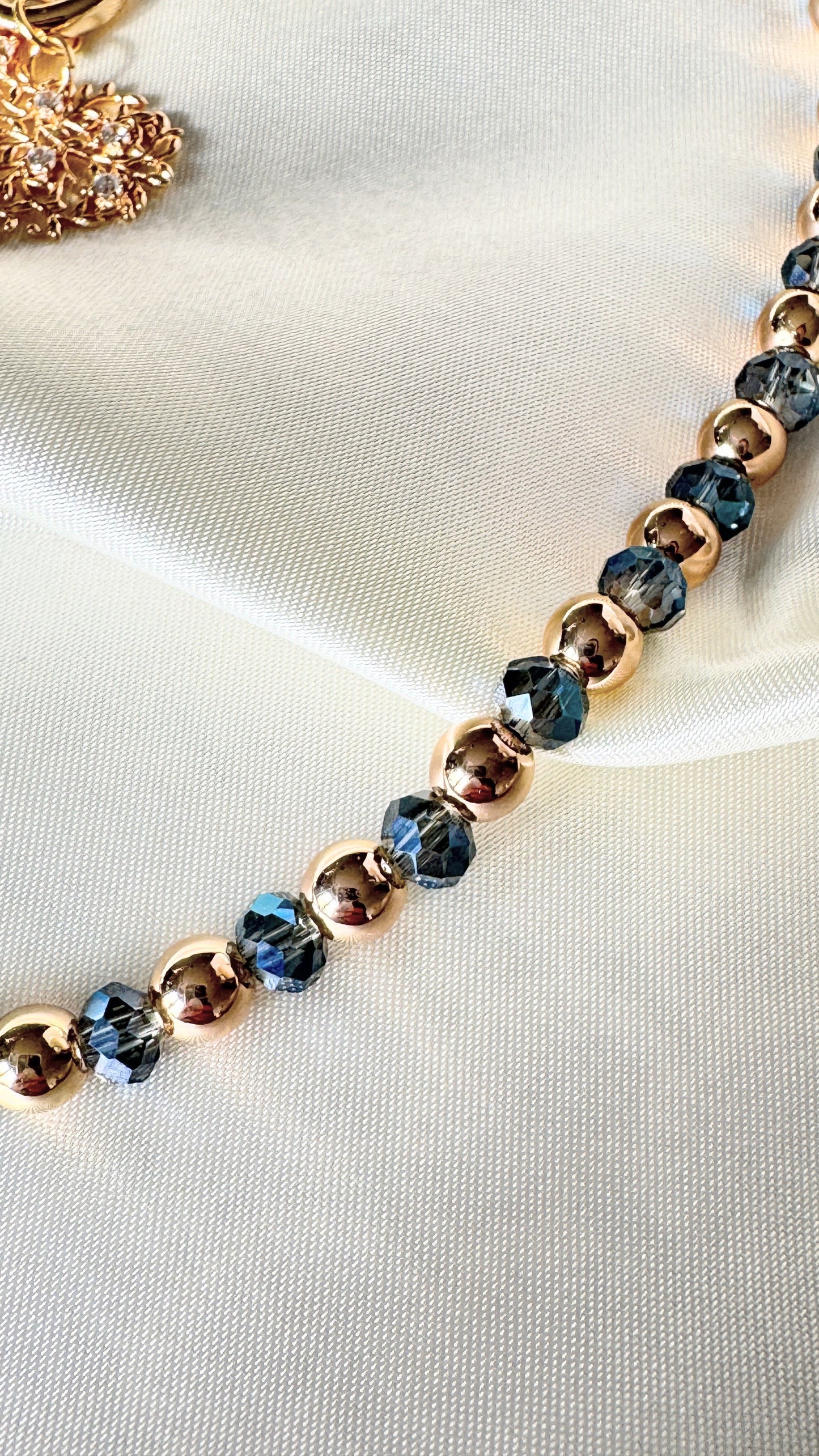 Elegant blue crystal hematite necklace with tree pendant displayed on fabric