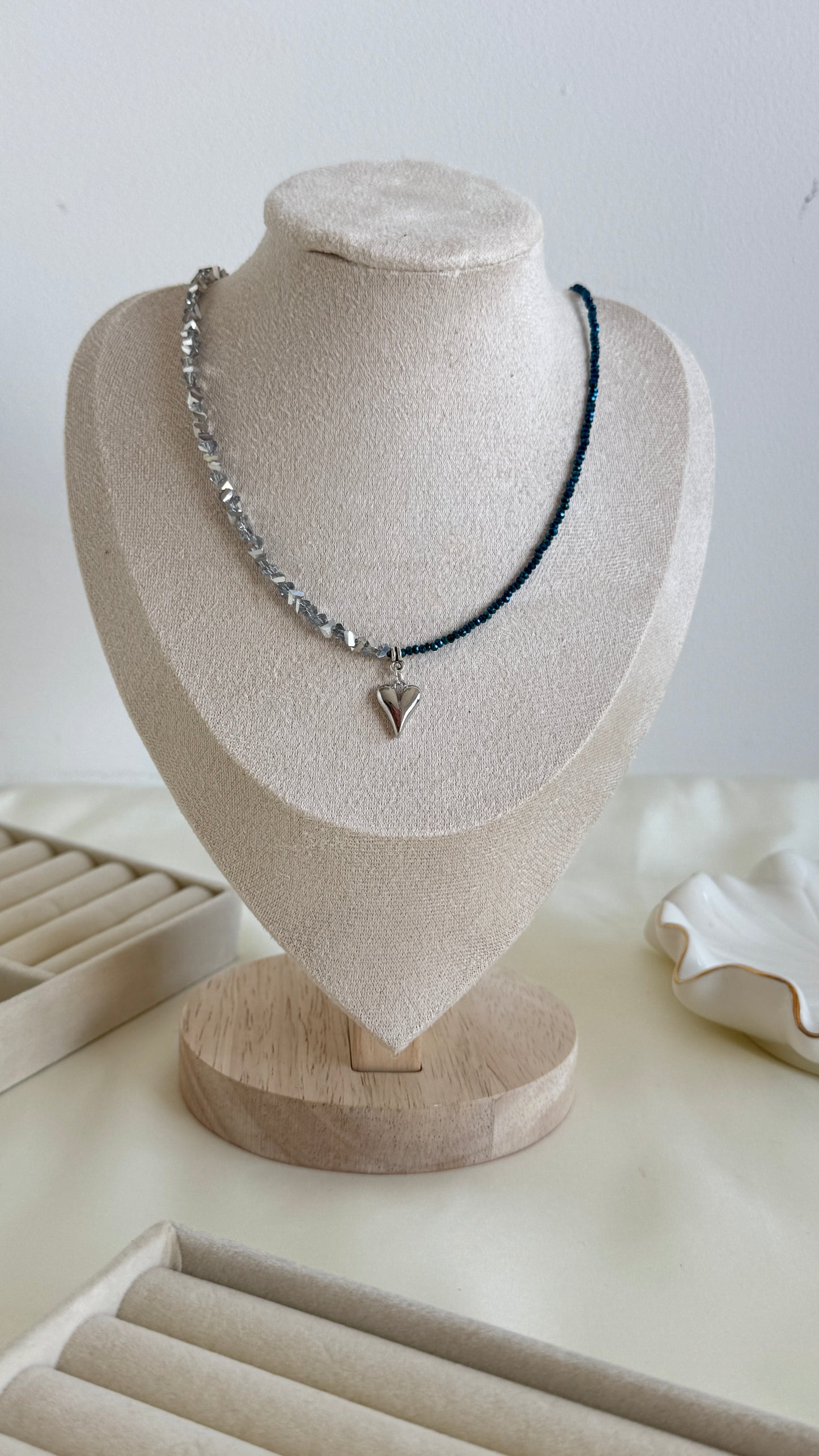 Minimalist necklace on cream background with half blue faceted beads and half silver hematite stones