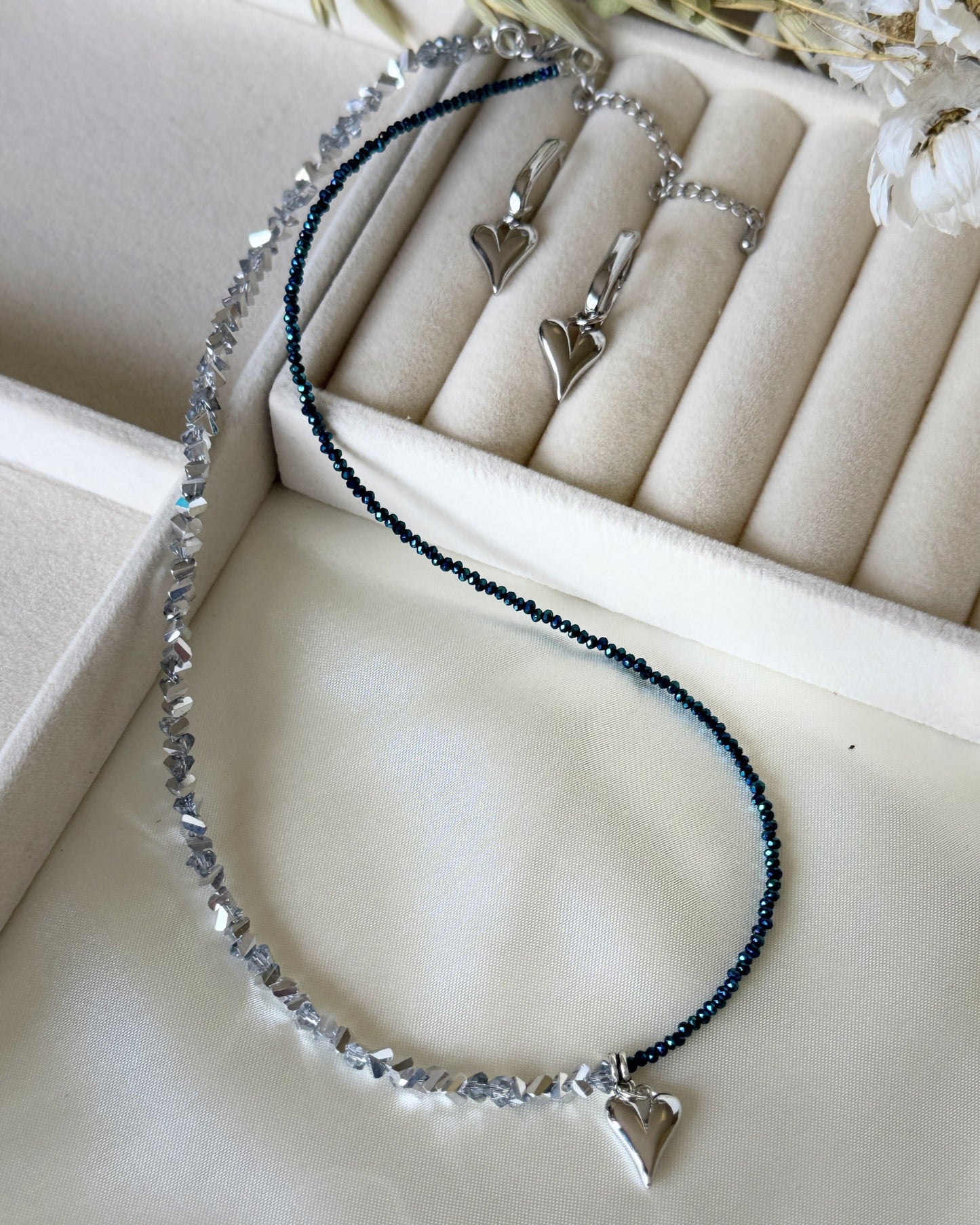 Elegant silver crystal heart jewelry set styled with soft fabric and decor