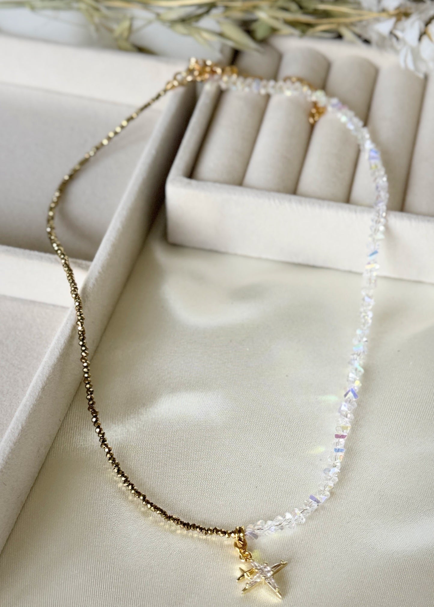 Close-up of star charms and hematite crystal beads on gold necklace