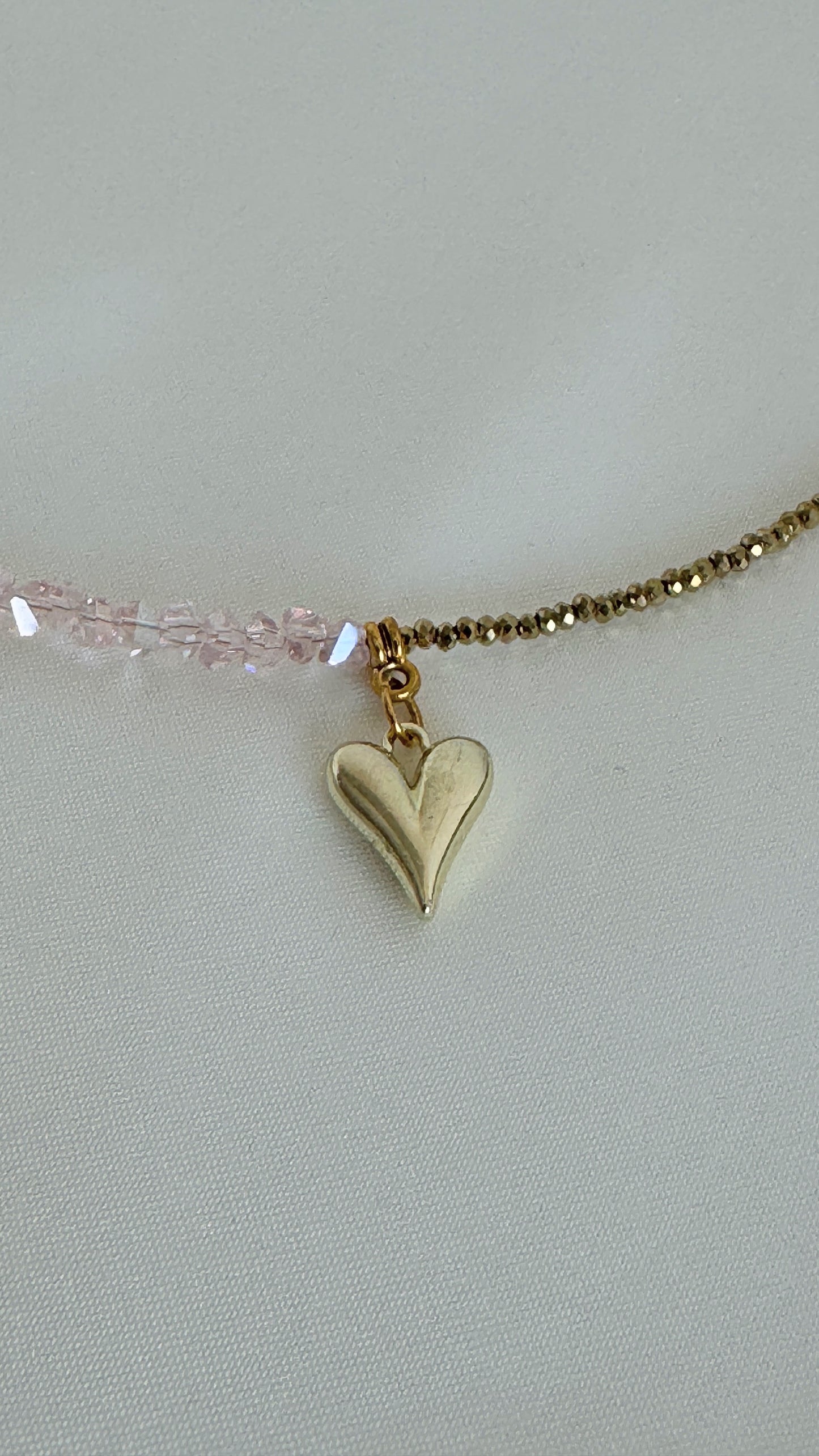 Detailed view of golden heart pendant with layered necklace