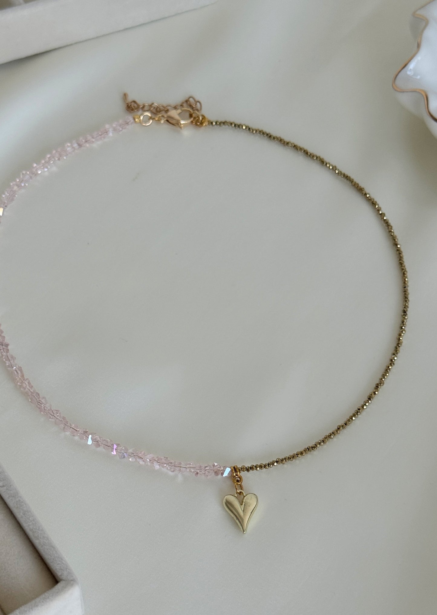 Detailed view of polished golden hematite beads and pink crystals on layered necklace