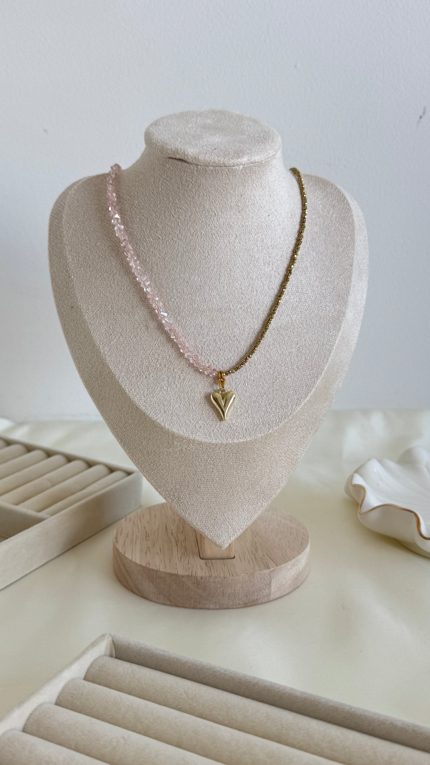 Elegant pink hematite bead necklace with gold accents displayed on necklace stand