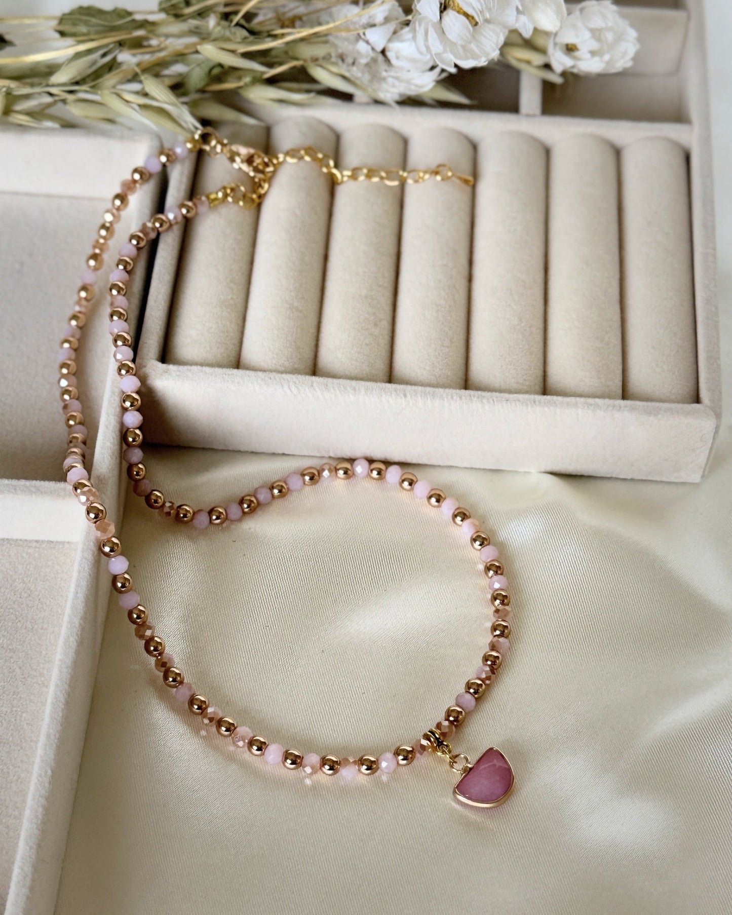 Light pink hematite and pearl necklace with gold accents on white background