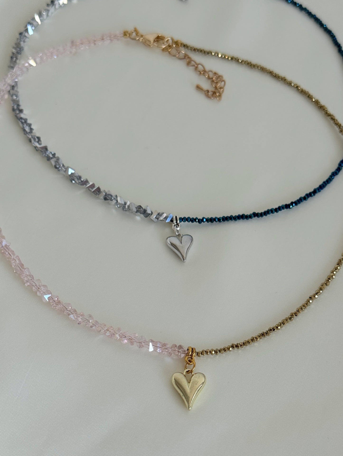 Two layered necklaces displayed together, one with golden beads and one with deep grey hematite beads