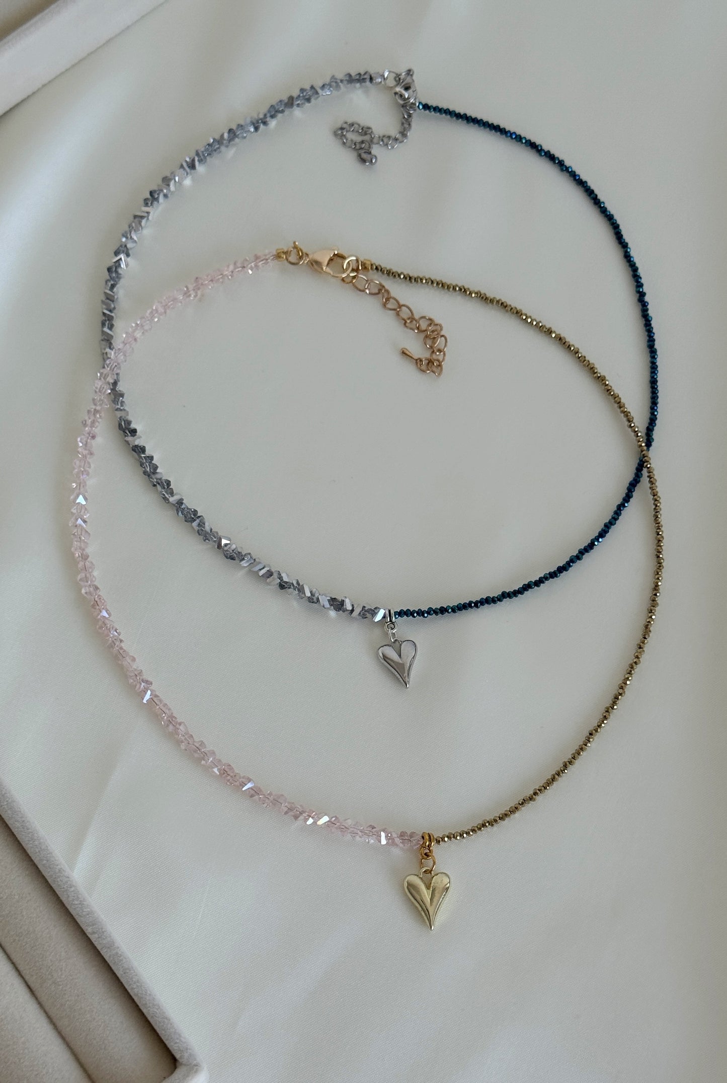 Stacked necklaces featuring golden beads and grey hematite beads styled for layering