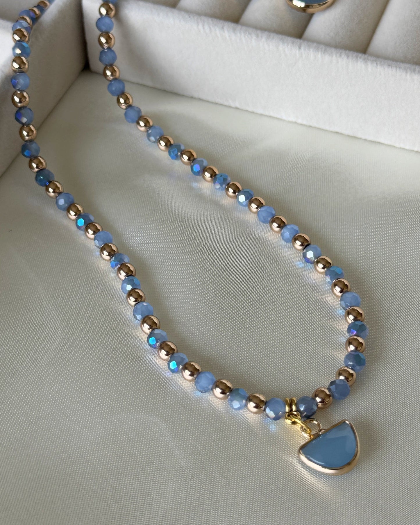 Blue gold hematite crystal necklace with layered gold chains on white background