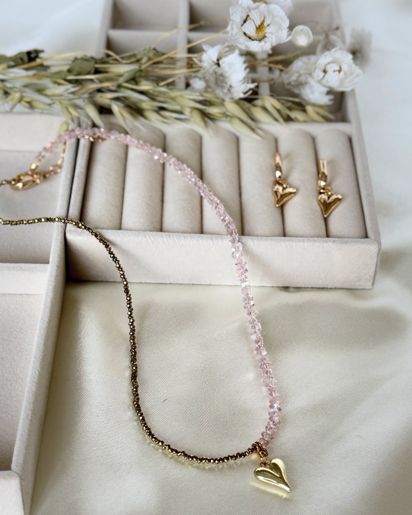 Pink gold hematite crystal necklace and earrings set displayed on fabric