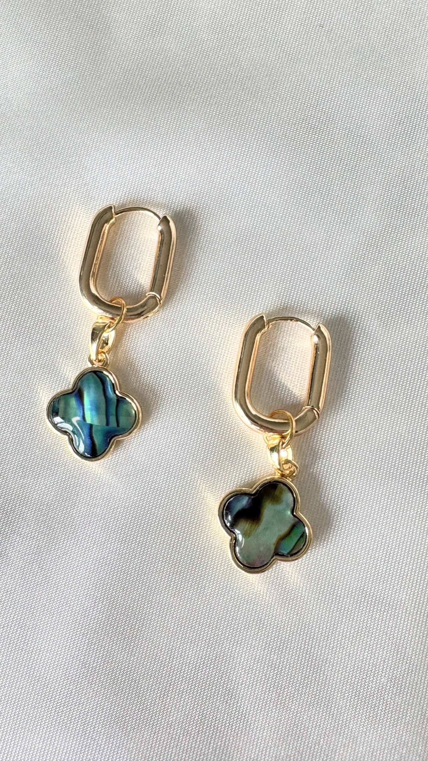 Close-up of dangling hematite crystal clover earrings with gold accents