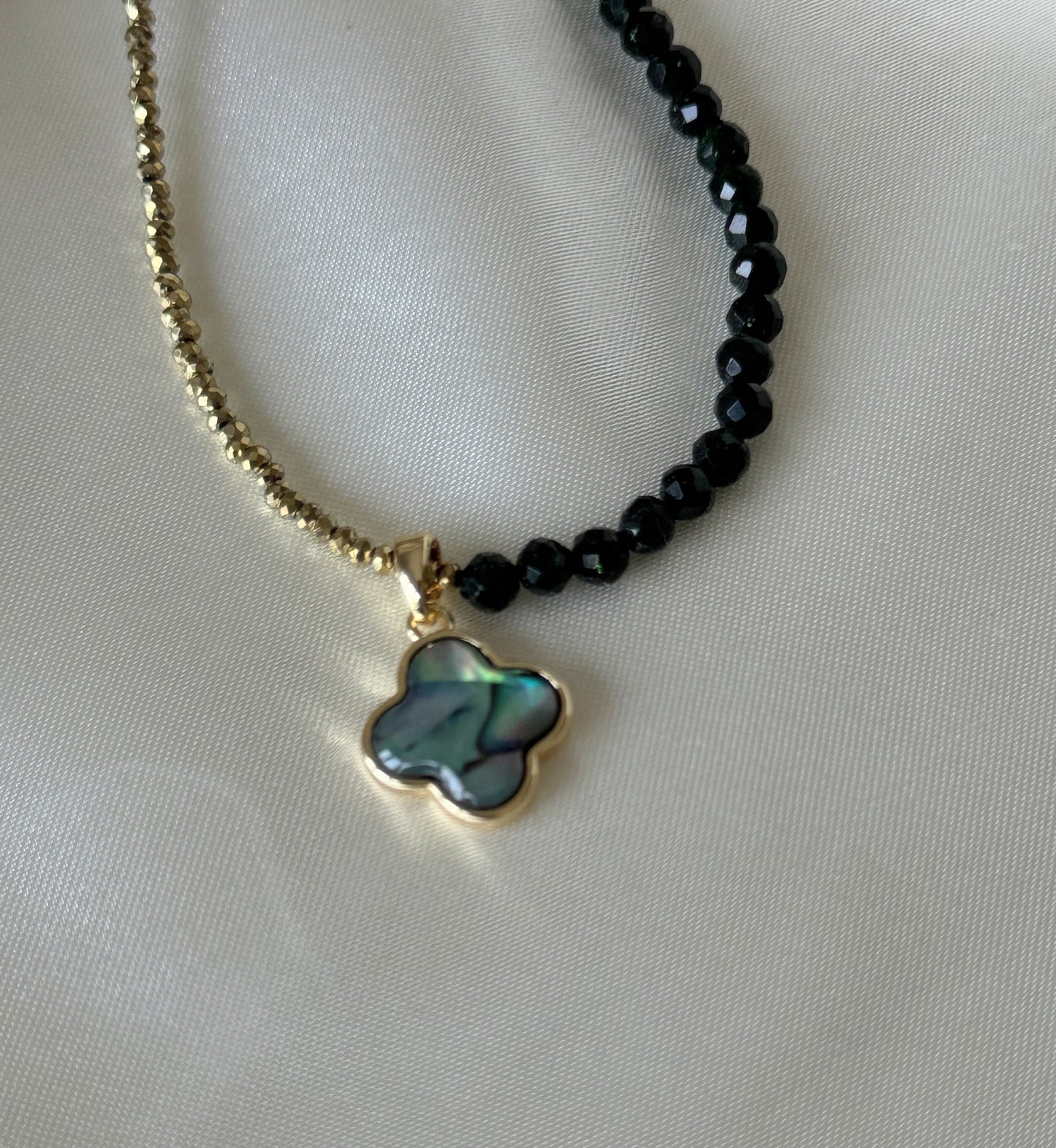 Elegant lucky clover hematite crystal necklace displayed on soft fabric
