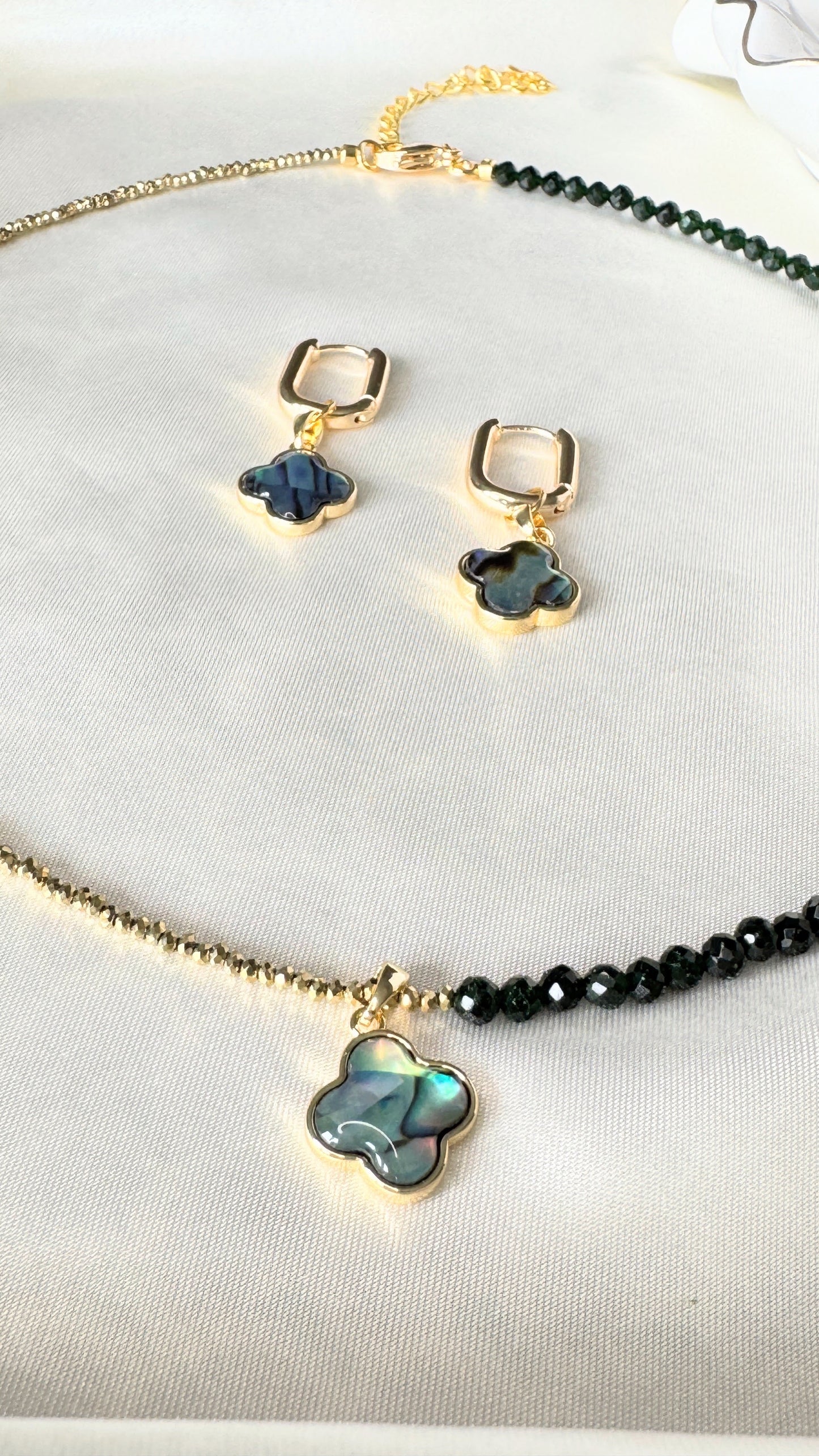 Close-up of lucky clover hematite necklace and earrings set with gold accents