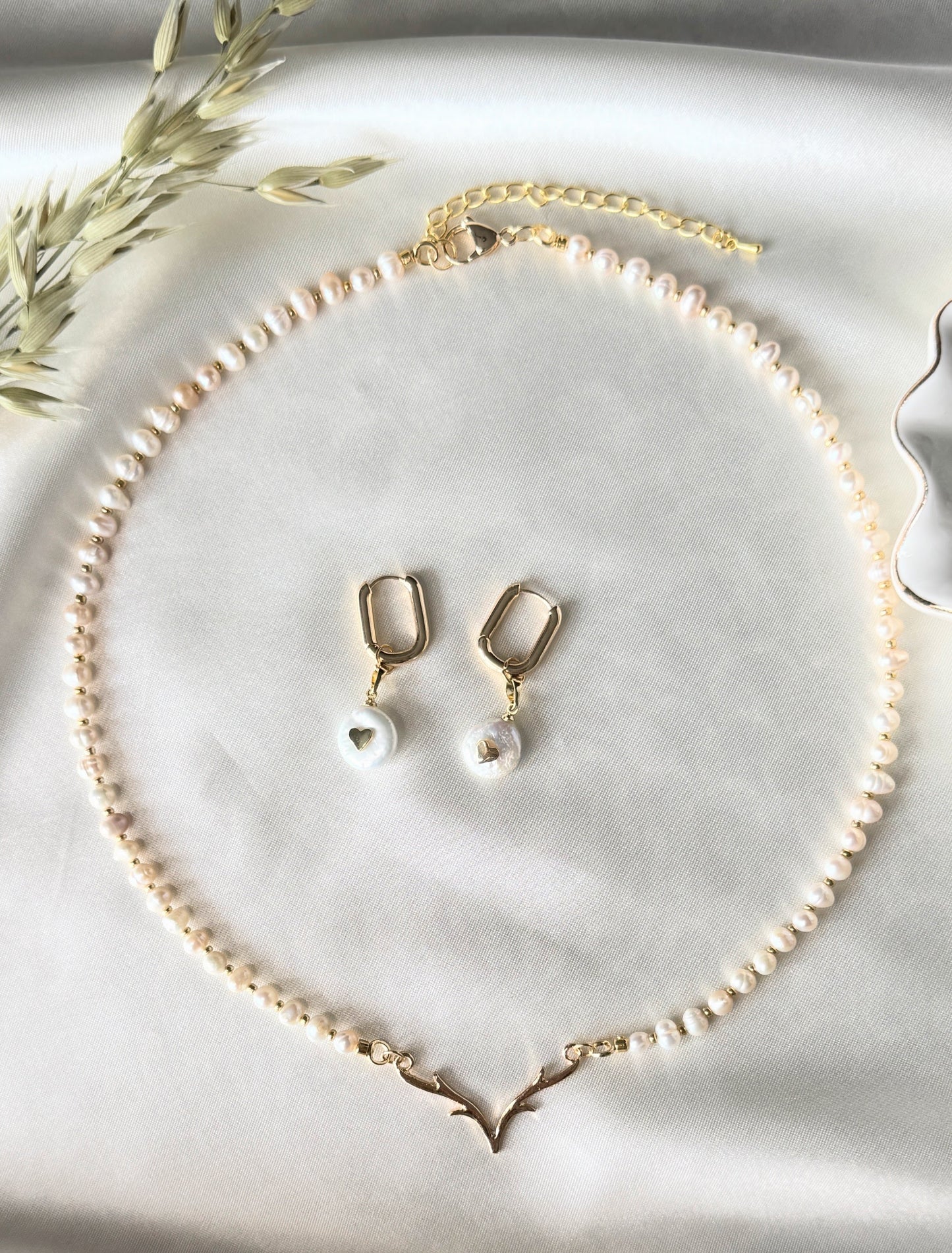 Deer pearl necklace and earrings set displayed on fabric with gold accents