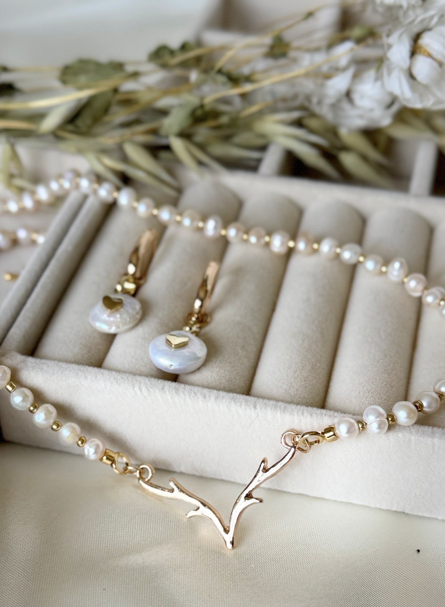 Close-up of deer antler pearl necklace and earrings set with gold accents