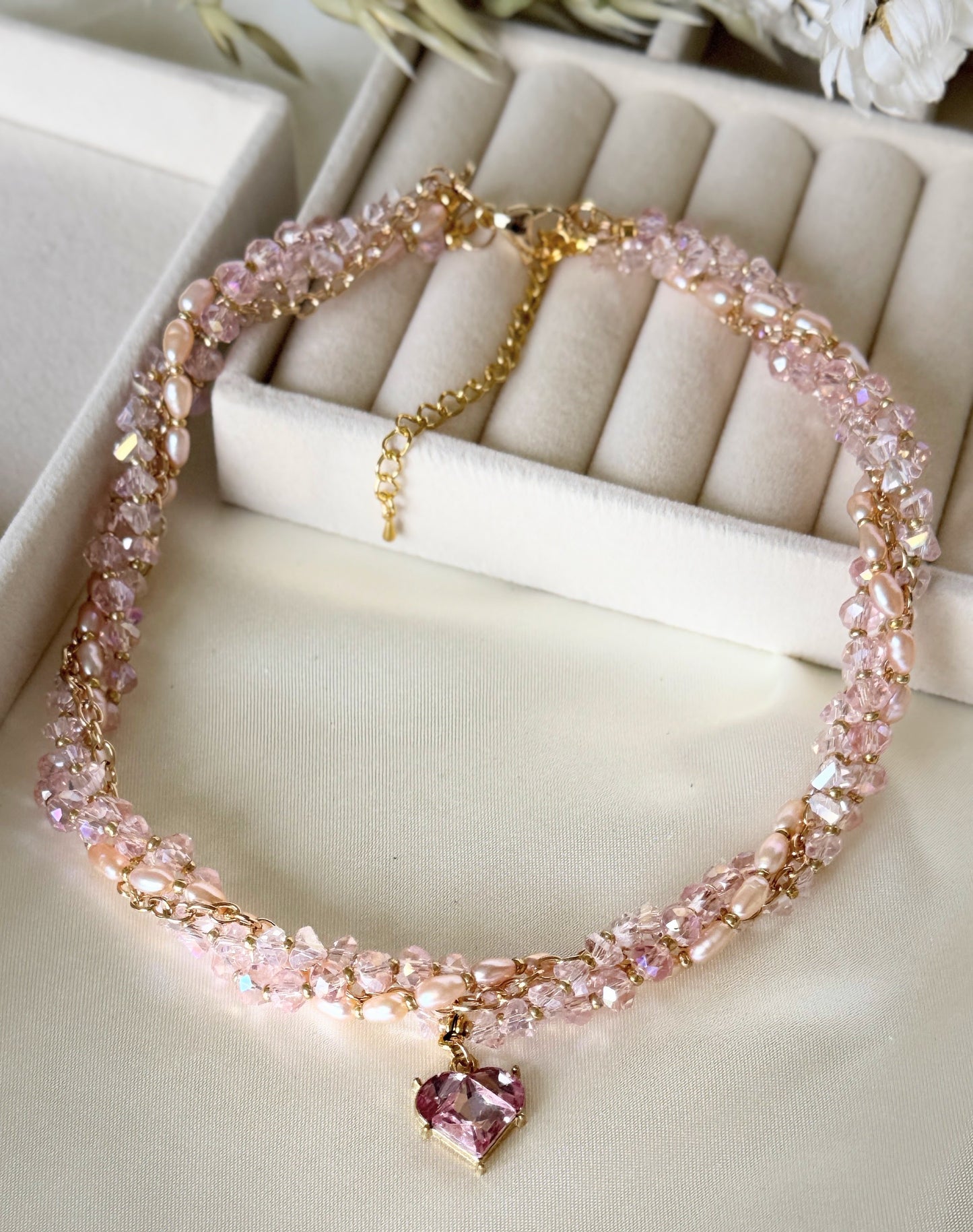 Pink layered crystal pearl necklace displayed on soft fabric background