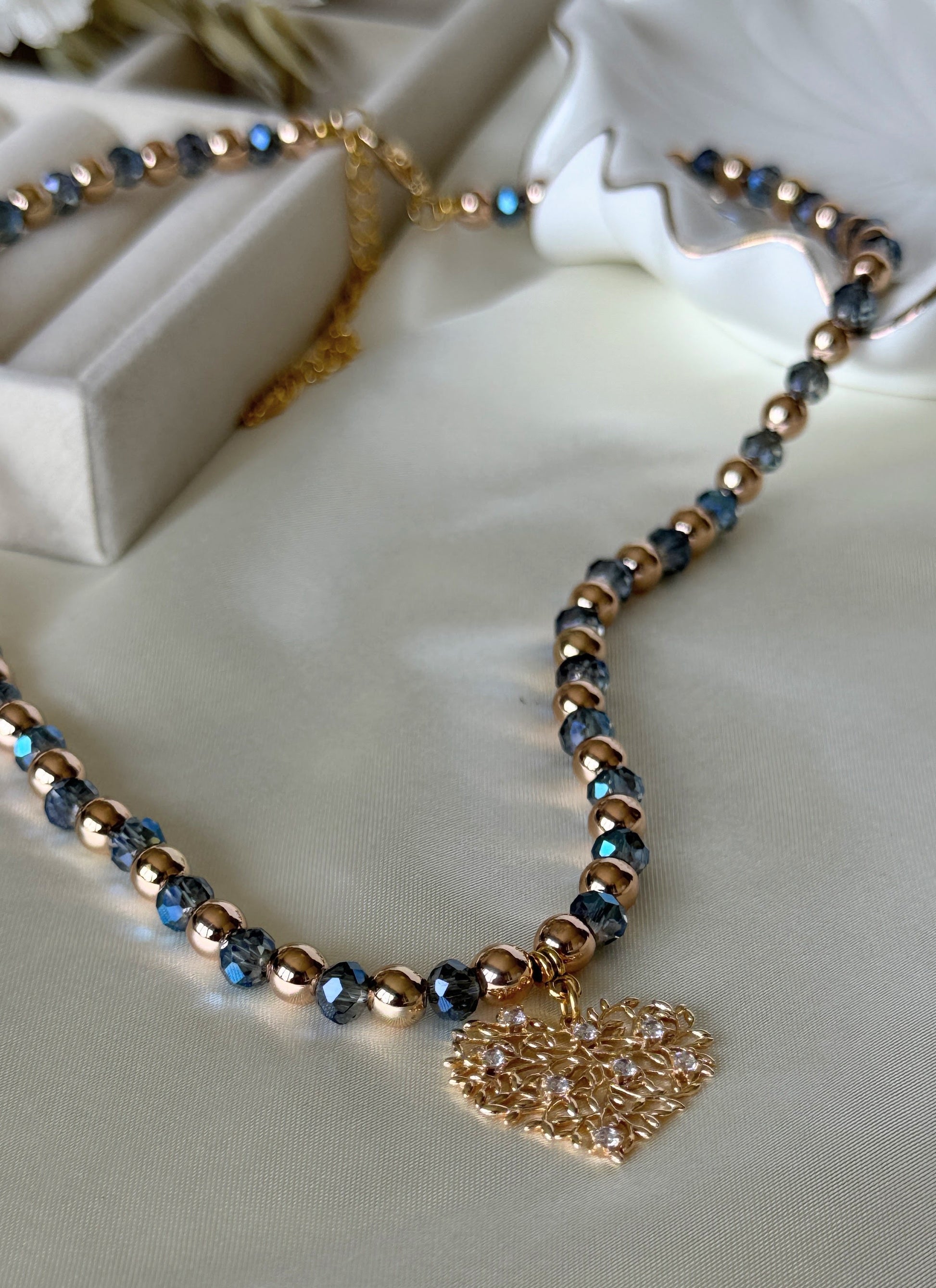 Close-up of blue crystal beads and hematite tree pendant on necklace