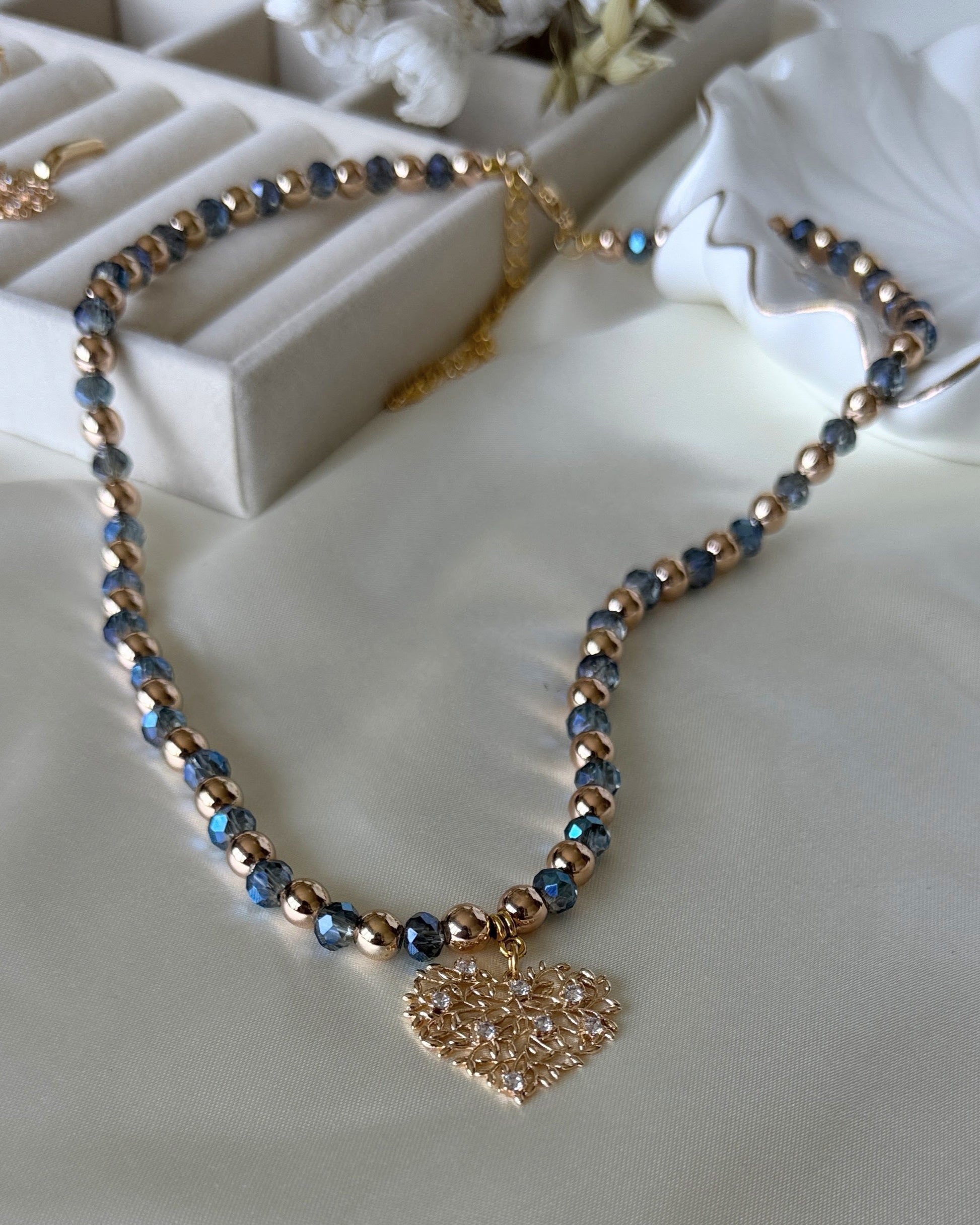 Tree blue crystal hematite necklace with layered gold chains on white background