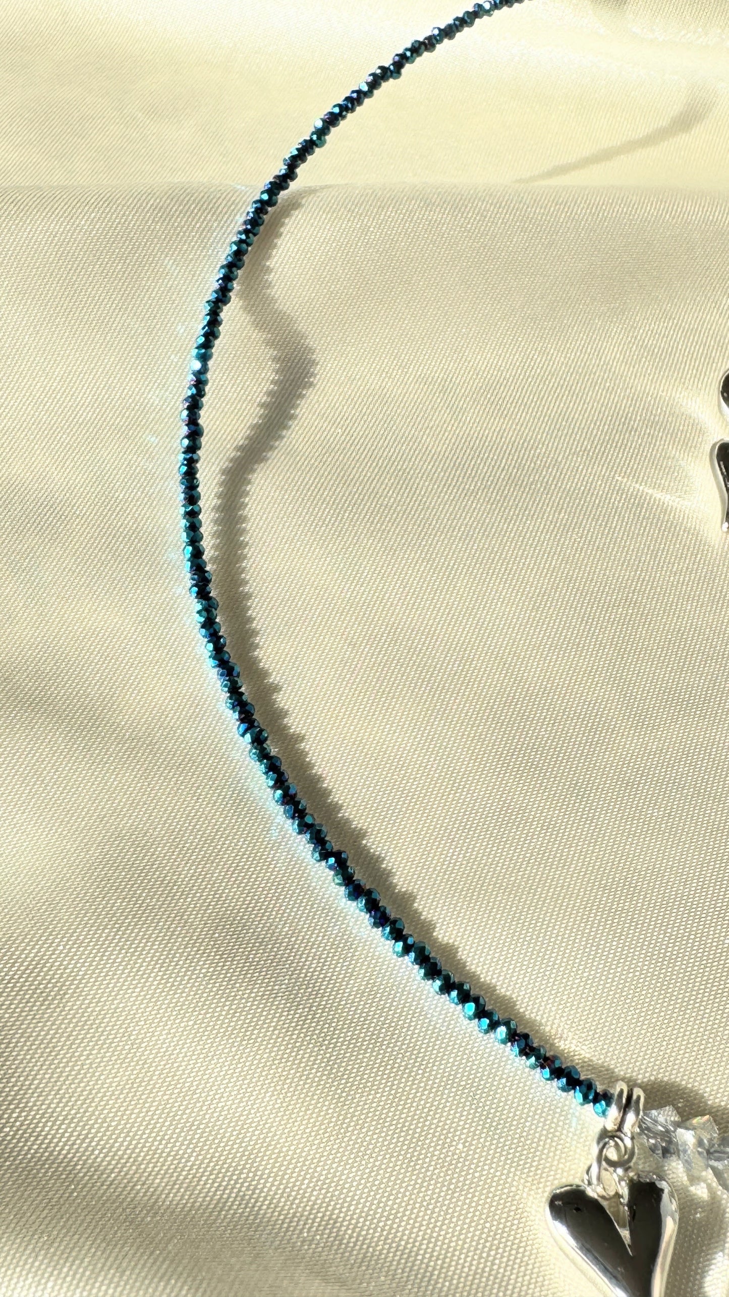 Close-up of silver heart pendant with hematite crystals on layered necklace