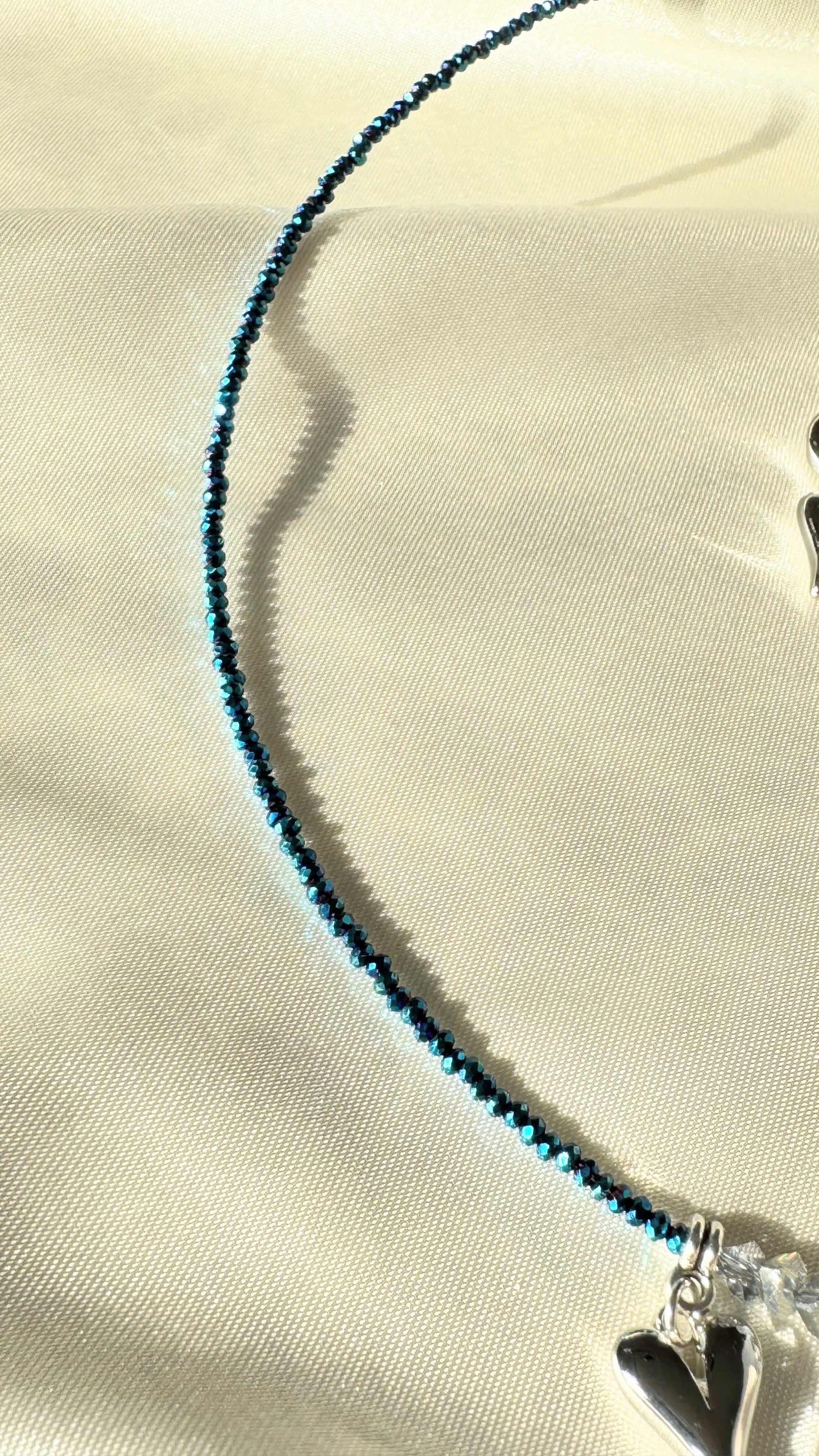 Close-up of silver heart pendant with hematite crystals on layered necklace