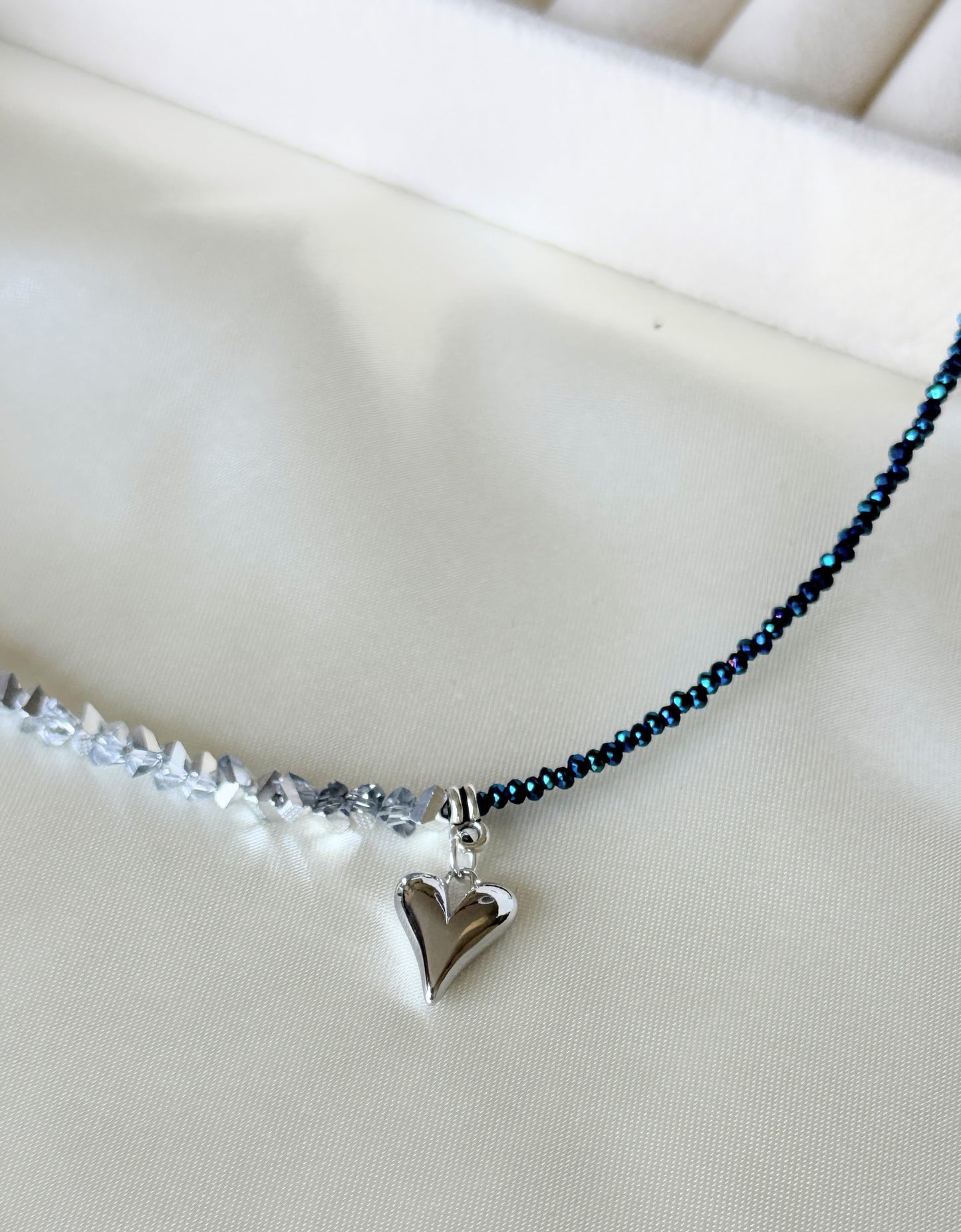 Hematite and silver crystal layered necklace displayed on fabric background