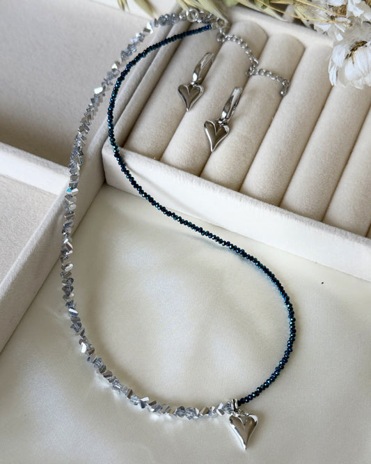 Elegant silver crystal heart jewelry set styled with soft fabric and decor