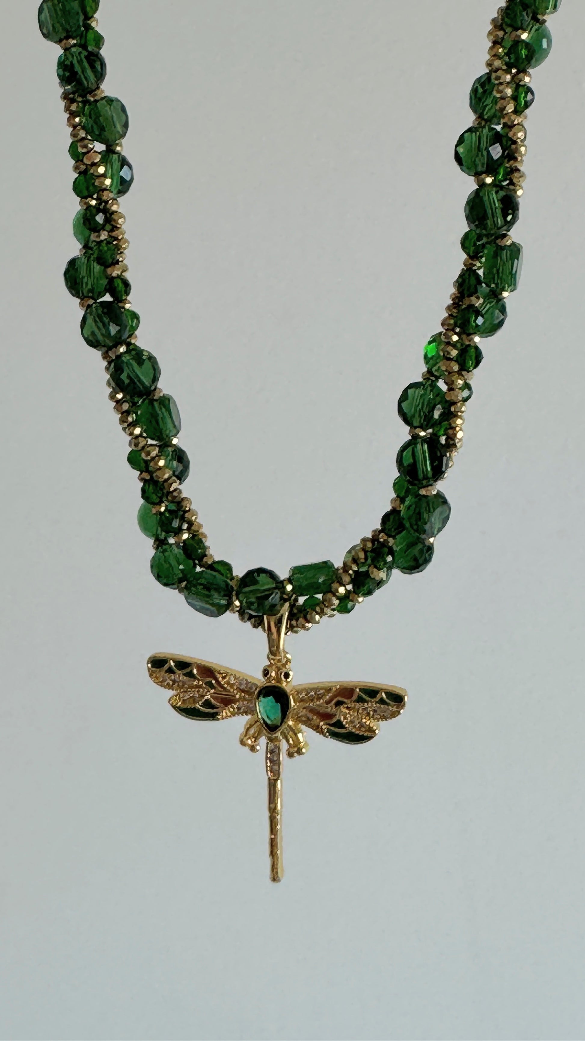 Fresh green crystal necklace with gold dragonfly pendant on soft fabric