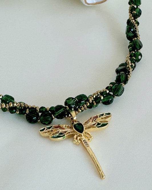 Green dragonfly crystal necklace with layered gold chains on white background