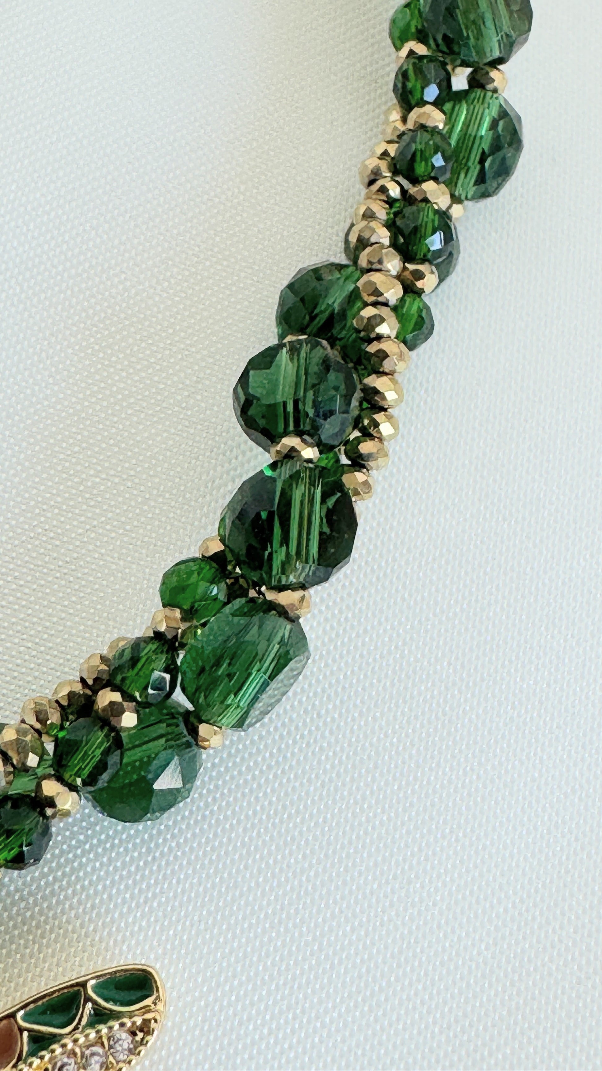 Elegant green dragonfly crystal necklace displayed on soft fabric