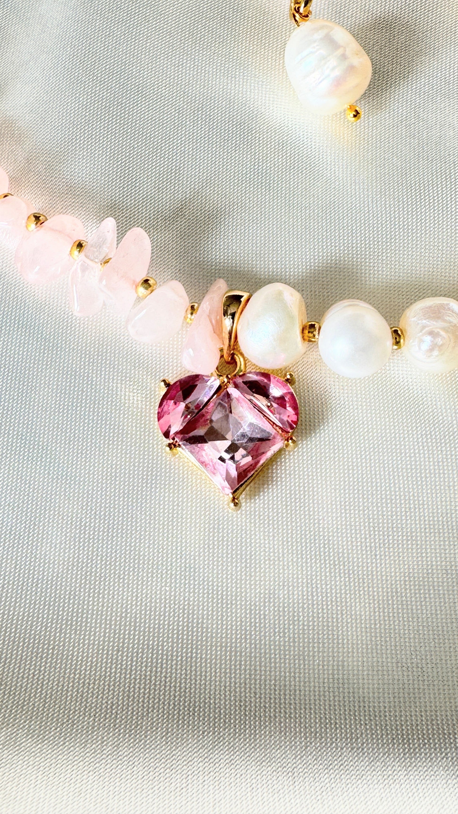 Elegant pink quartz and pearl necklace displayed on soft fabric