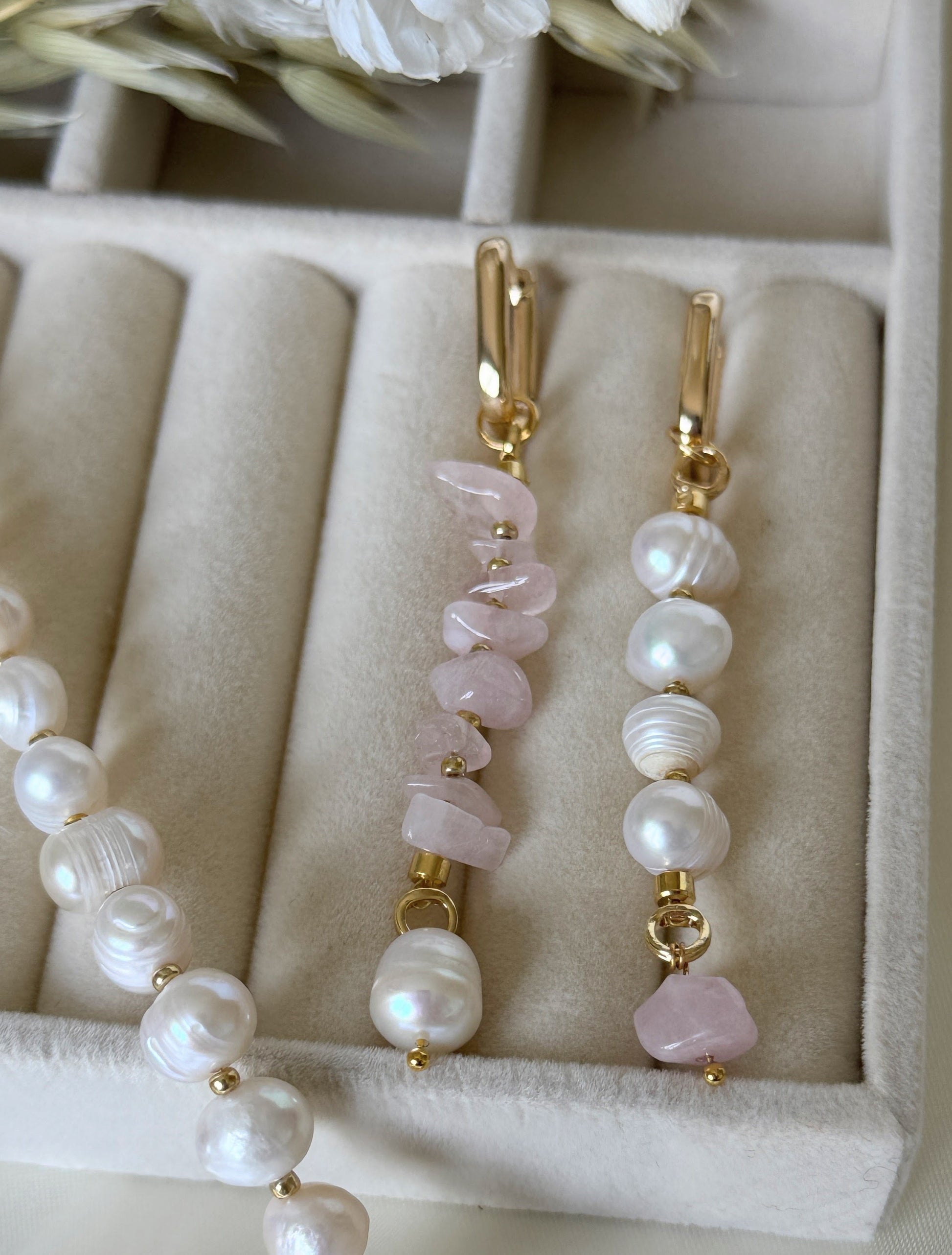 Close-up of pink quartz crystal and pearl earrings with gold accents