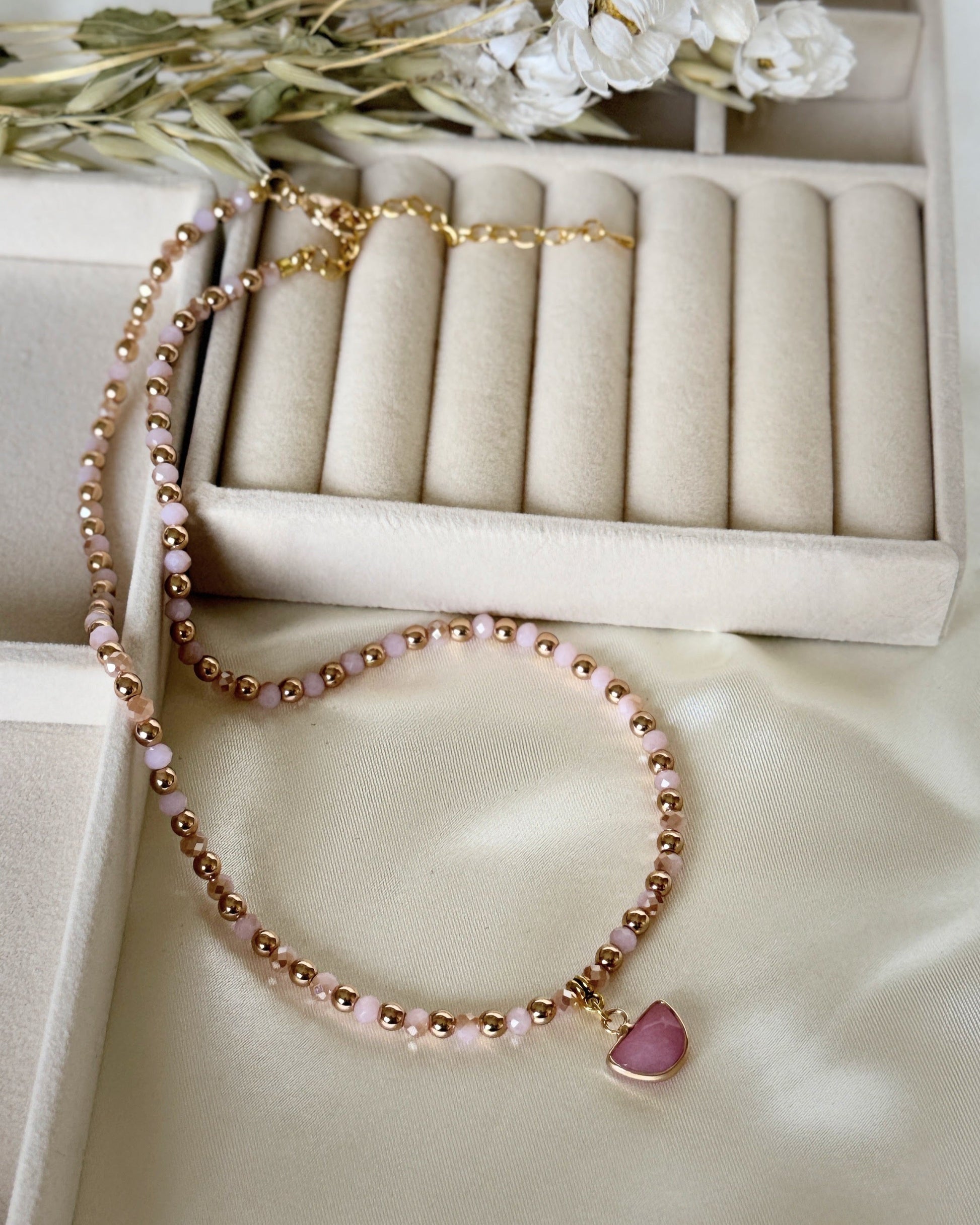 Light pink hematite and pearl necklace with gold accents on white background