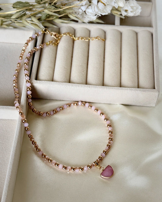 Light pink hematite and pearl necklace with gold accents on white background