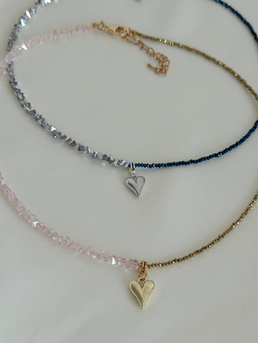 Two layered necklaces displayed together, one with golden beads and one with deep grey hematite beads