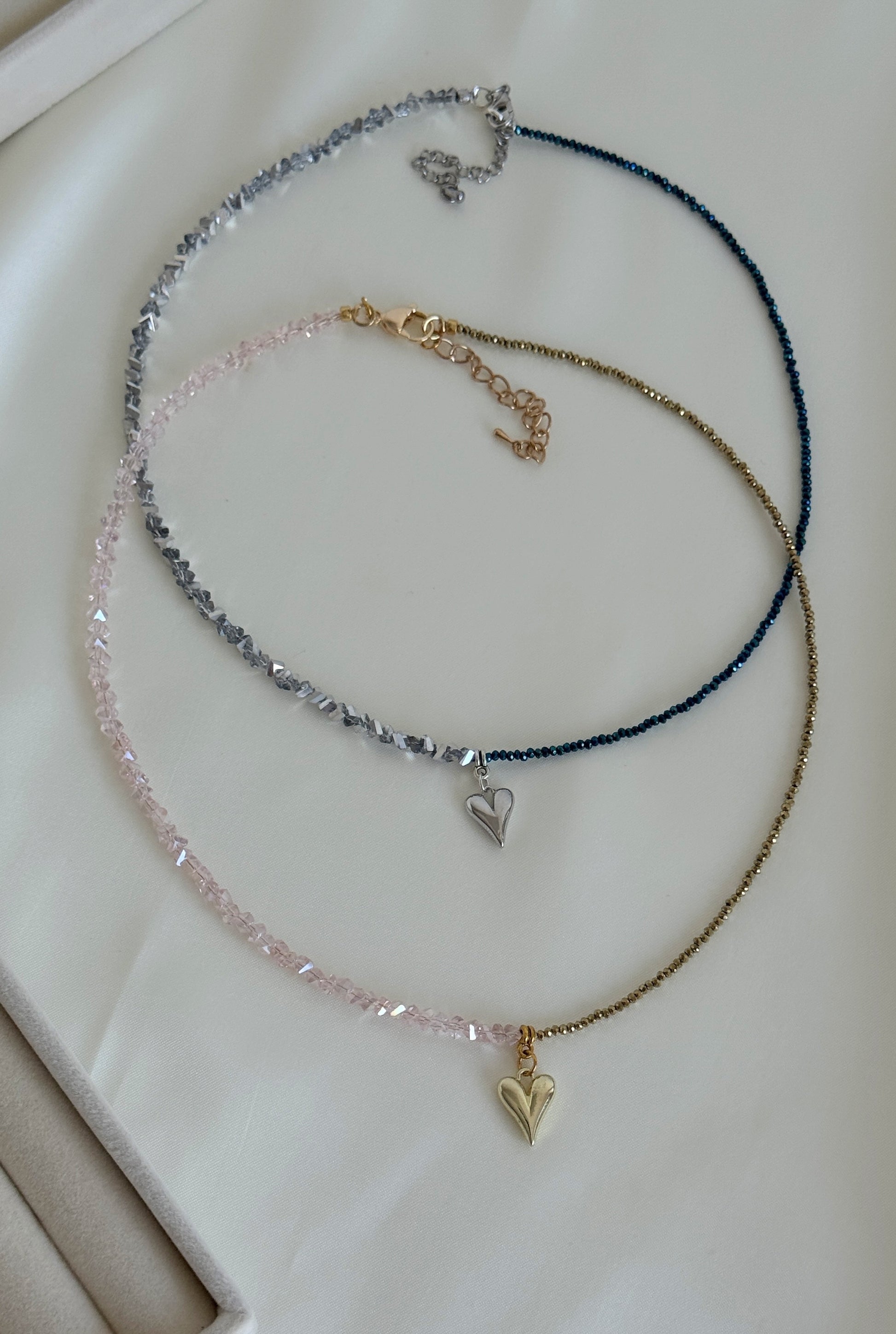Stacked necklaces featuring golden beads and grey hematite beads styled for layering