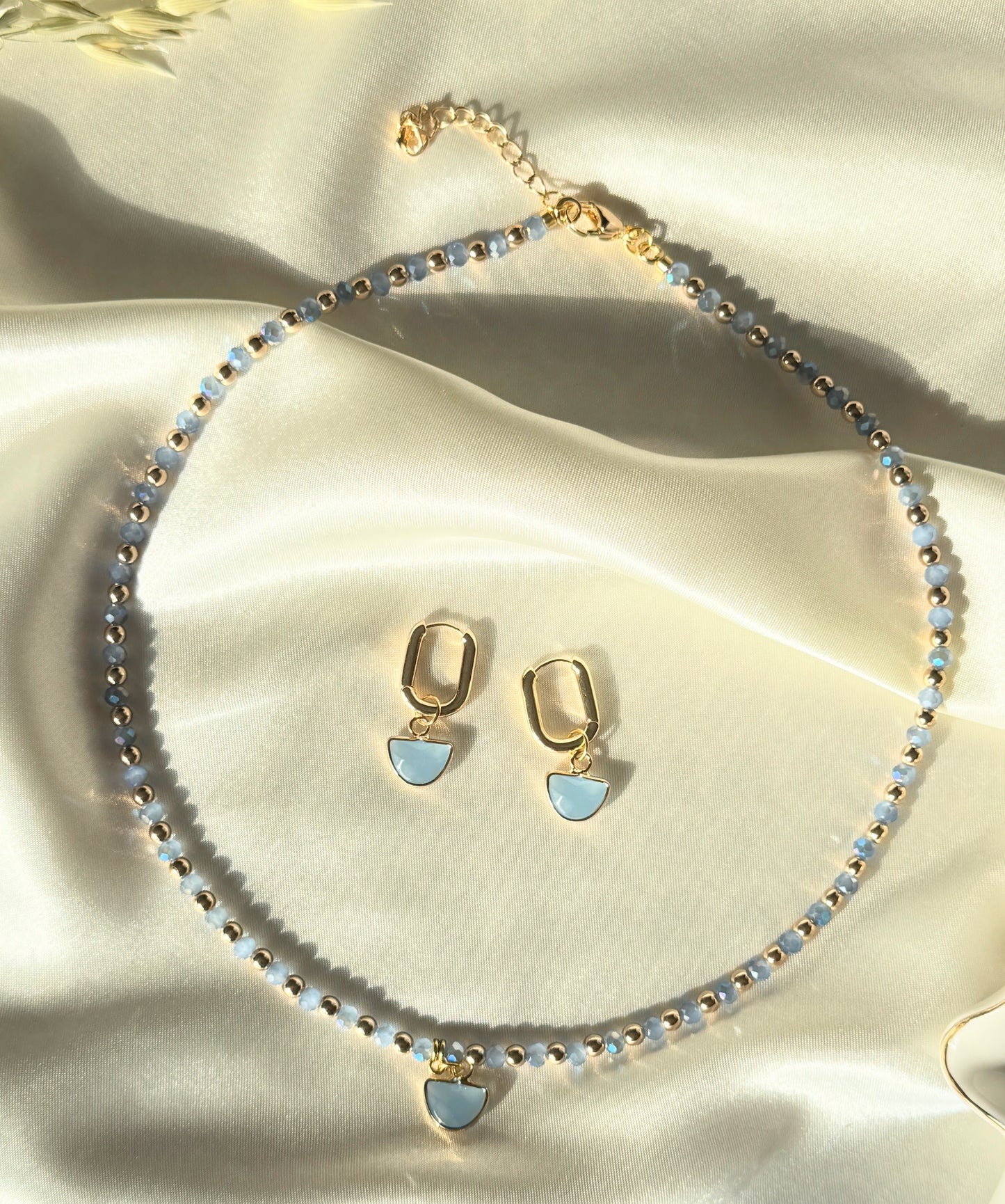 Blue gold hematite crystal necklace and earrings set displayed on fabric