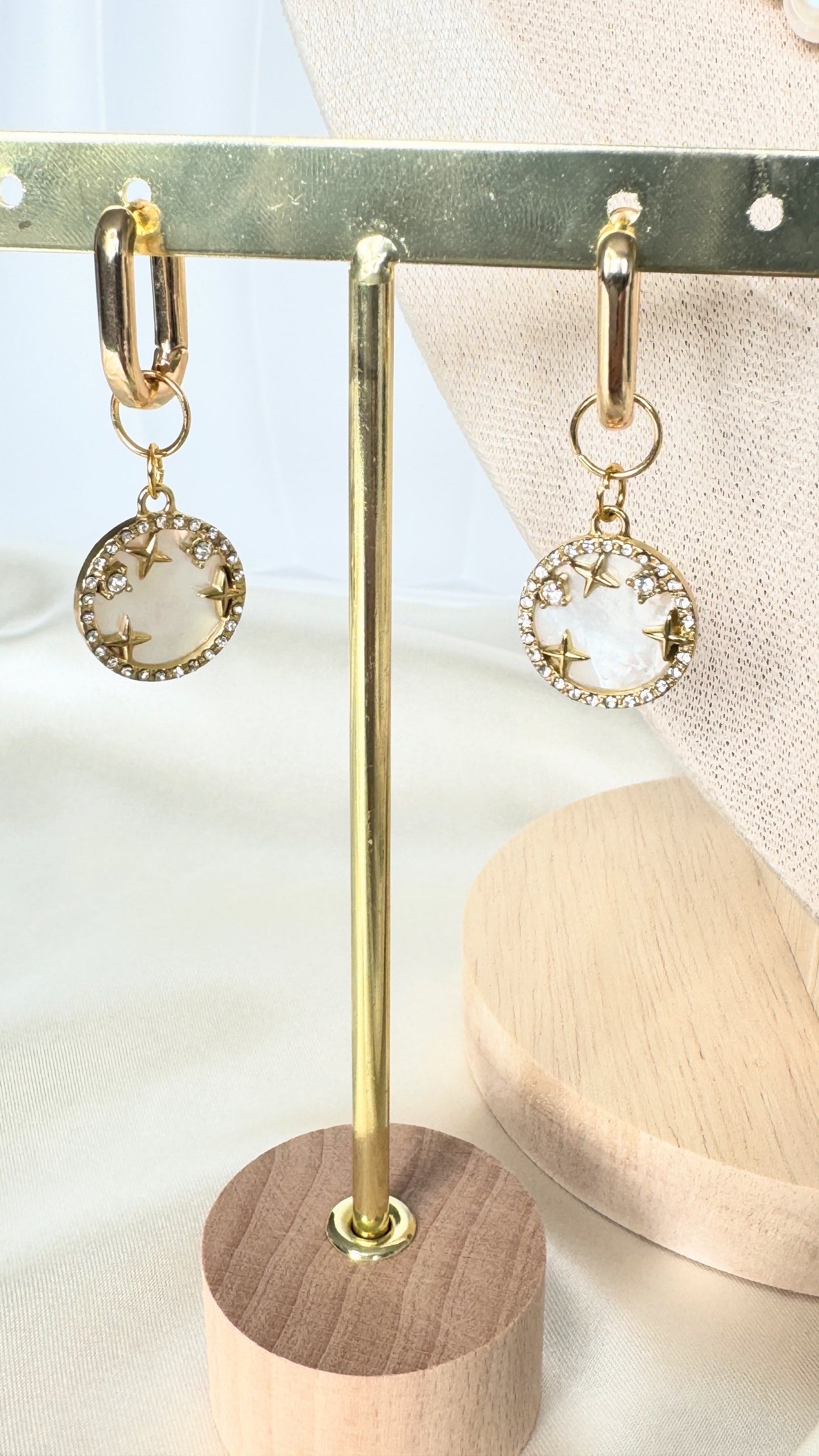 Dangling mother-of-pearl earrings with gold accents on jewelry tray