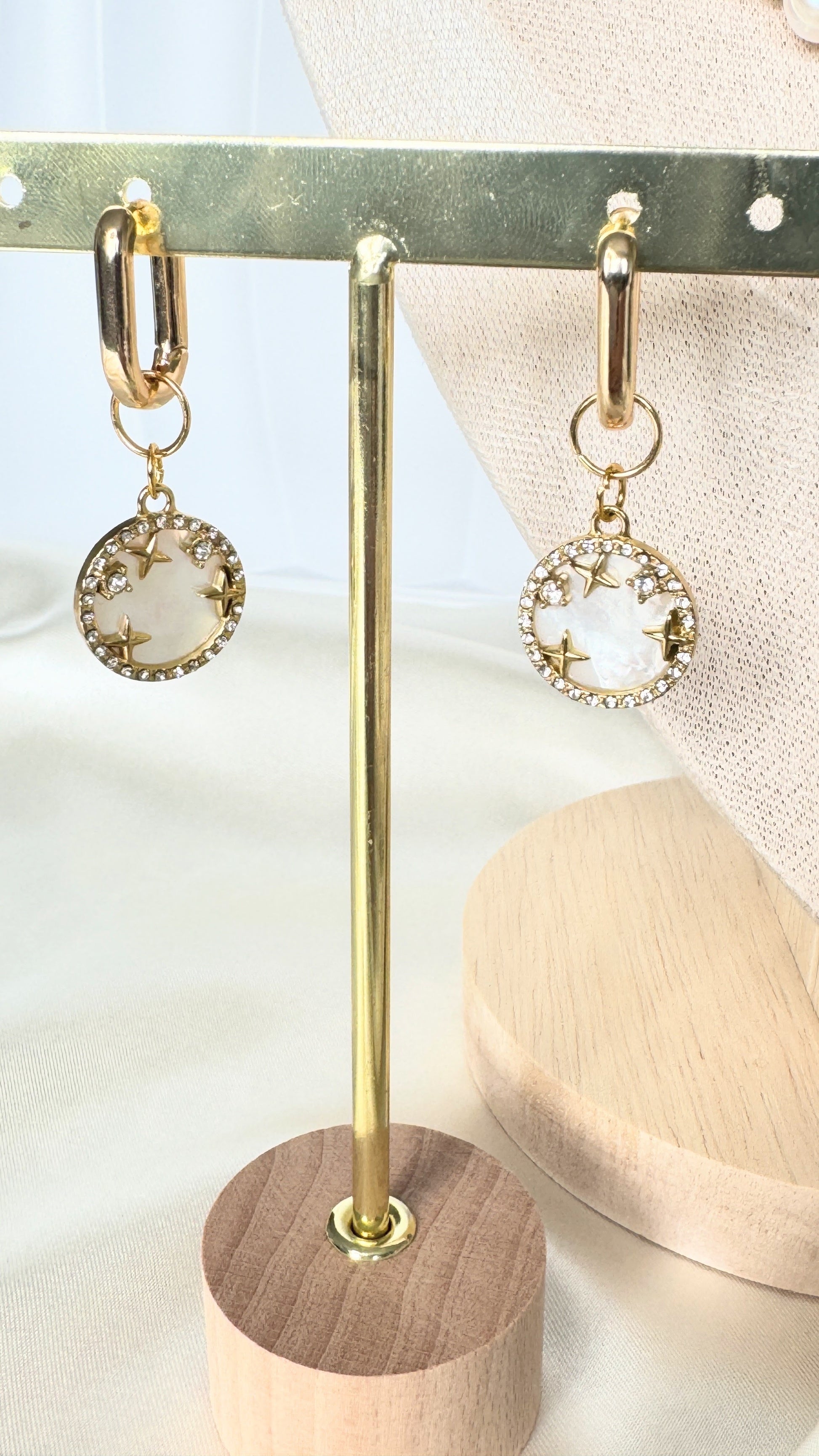 Dangling mother-of-pearl earrings with gold accents on jewelry tray