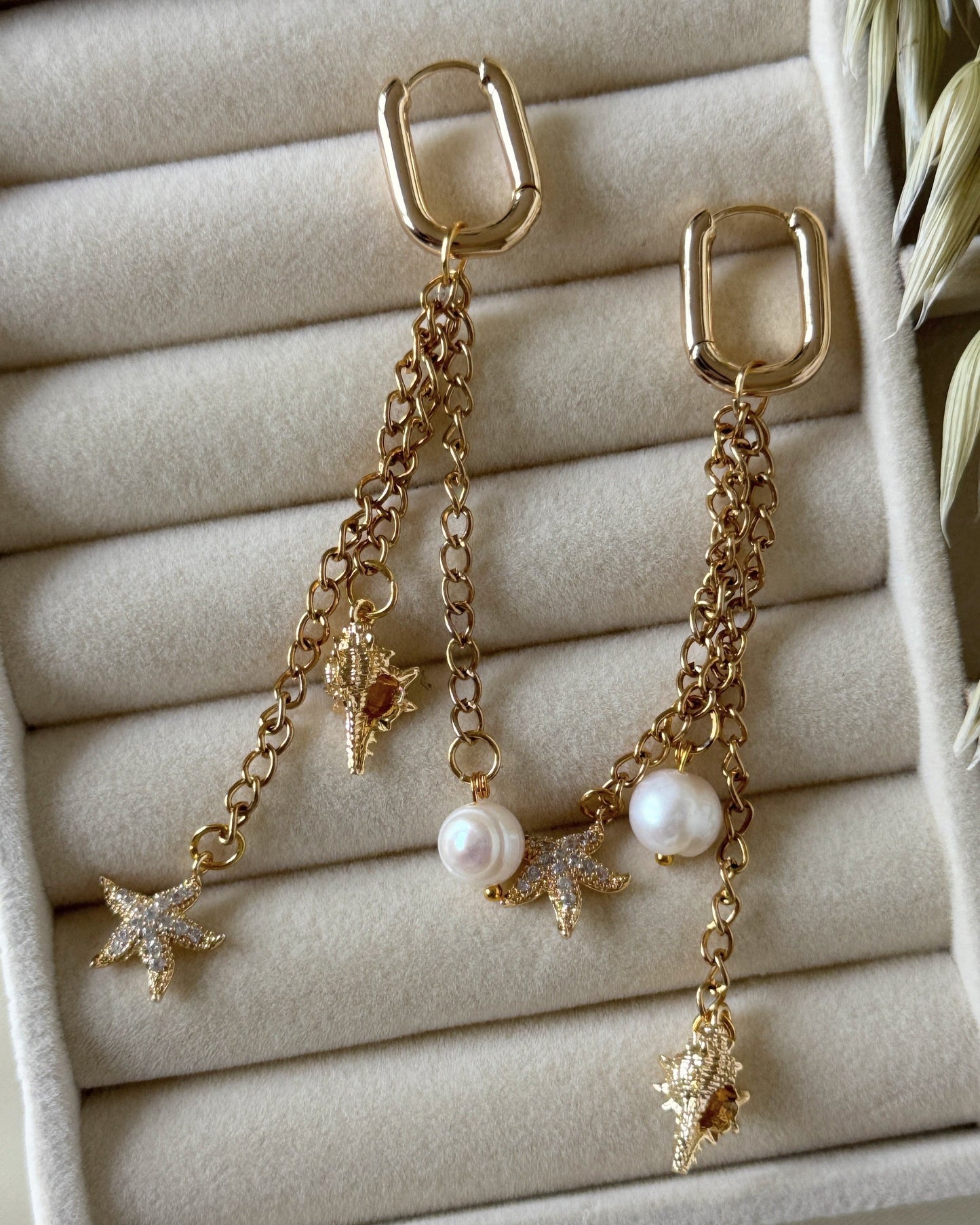 Elegant golden pearl earrings displayed on jewelry tray