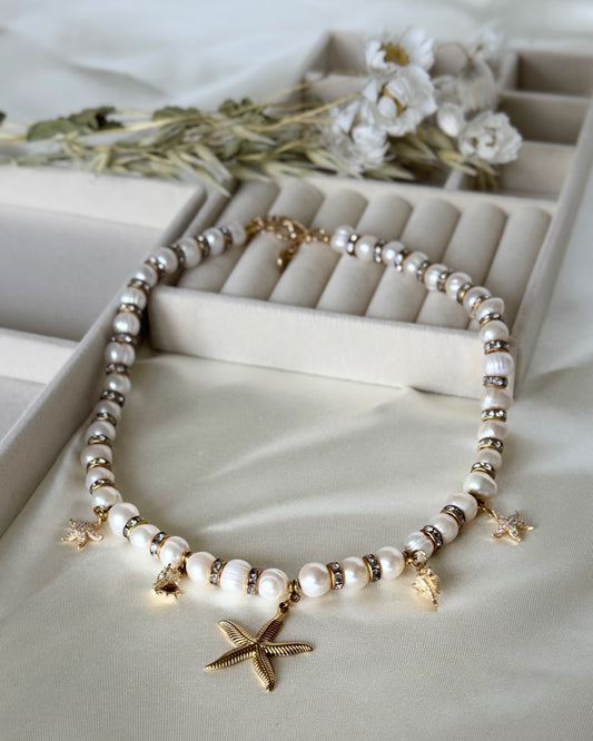 Golden sea pearl necklace with layered gold chains on white background