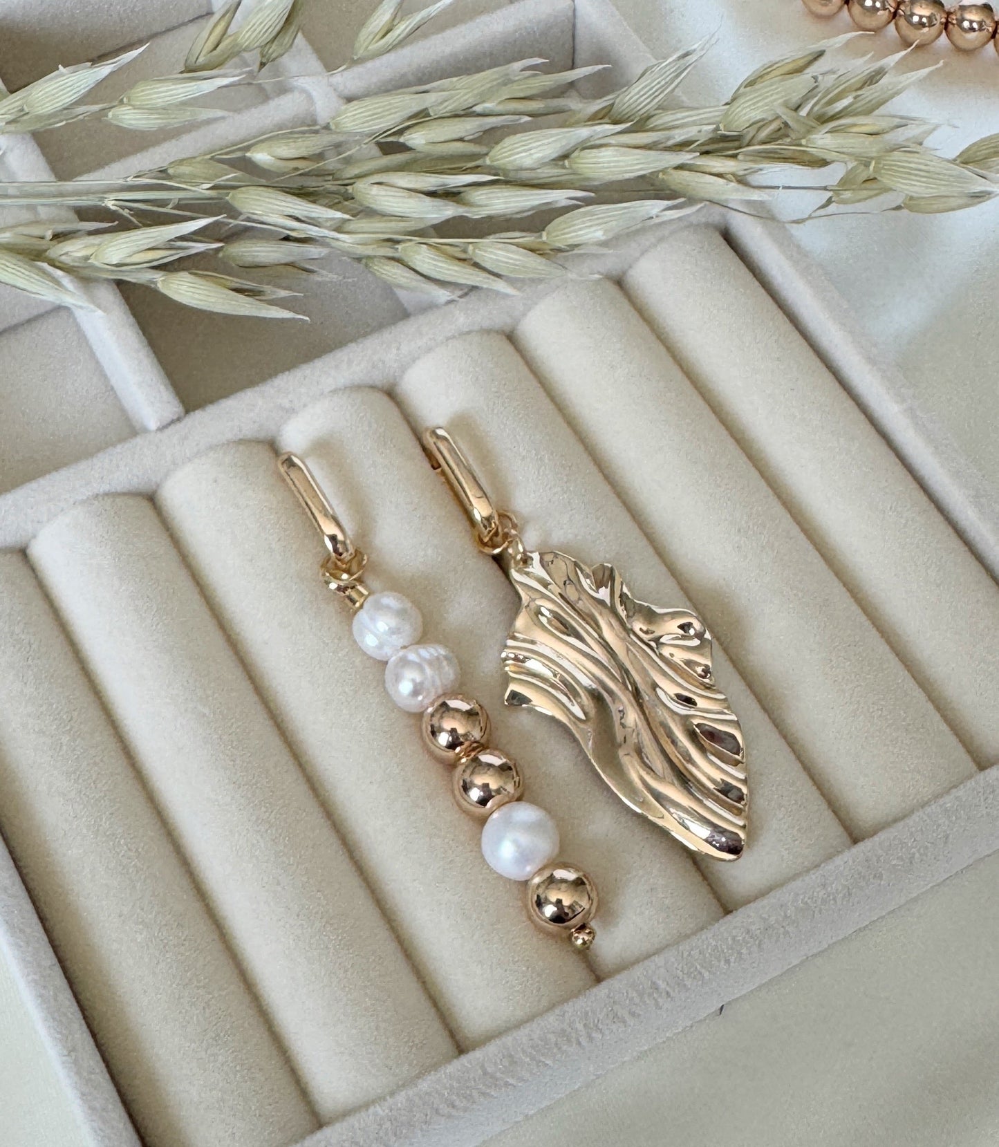 Elegant golden hematite and pearl earrings displayed on jewelry tray