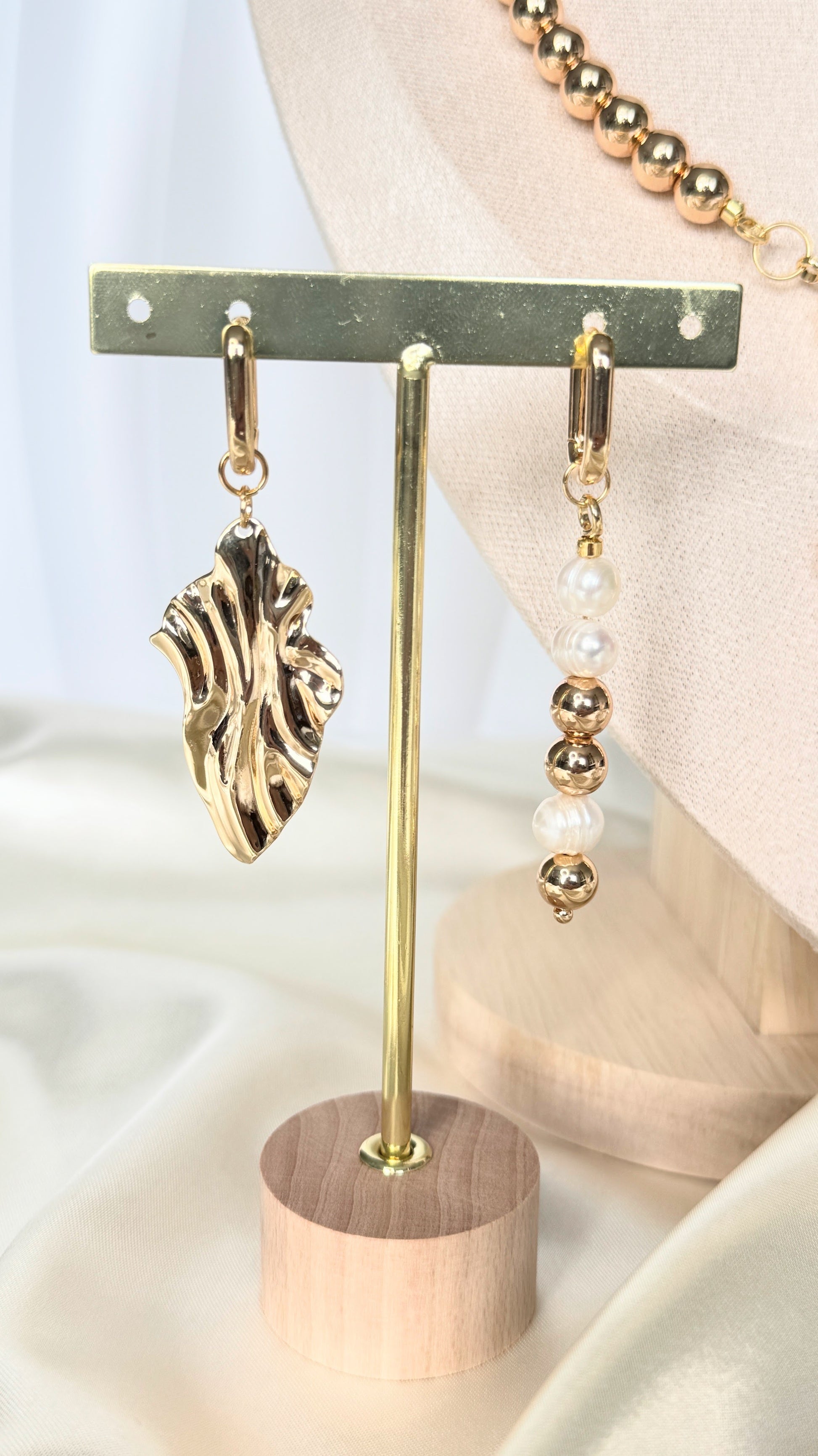 Golden hematite pearl earrings with gold details on fabric background