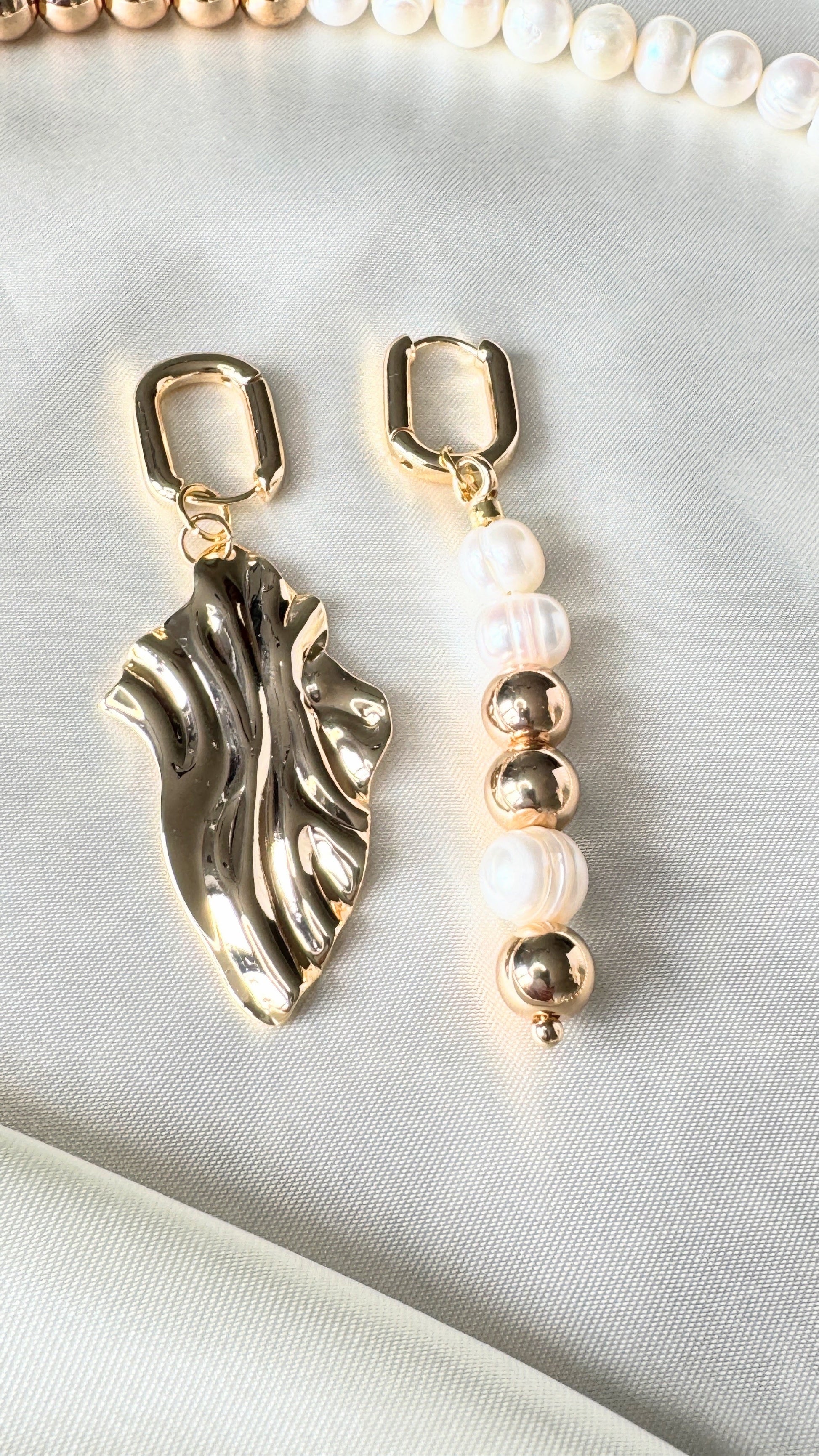 Elegant golden hematite and pearl earrings displayed on jewelry tray with beads decor
