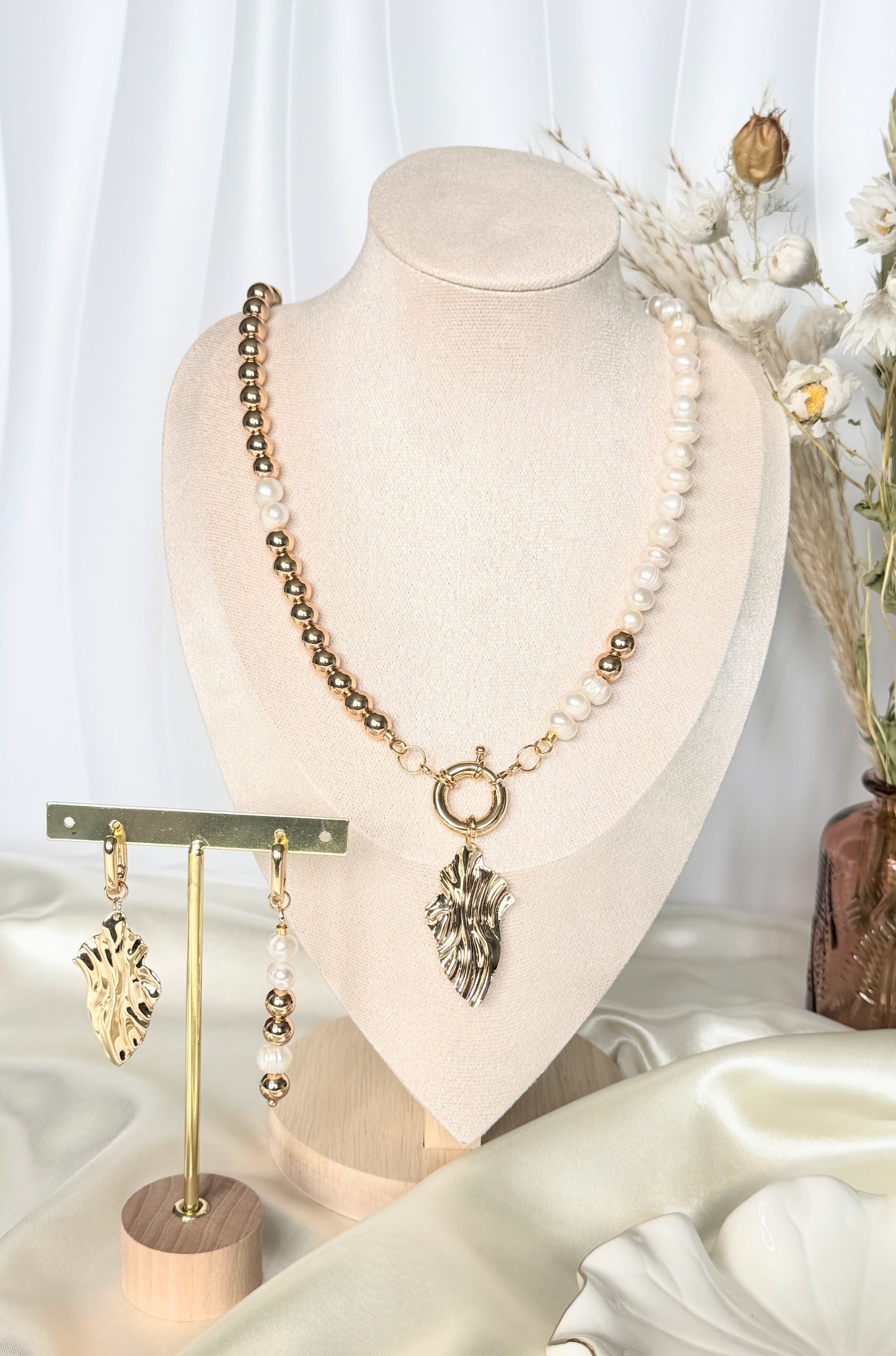Elegant golden hematite pearl necklace with earrings displayed on jewelry stand