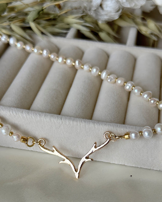 Deer pearl necklace with gold antler pendant on white background