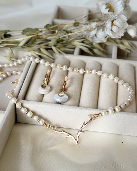 Deer pearl jewelry set with necklace and dangling earrings displayed on fabric