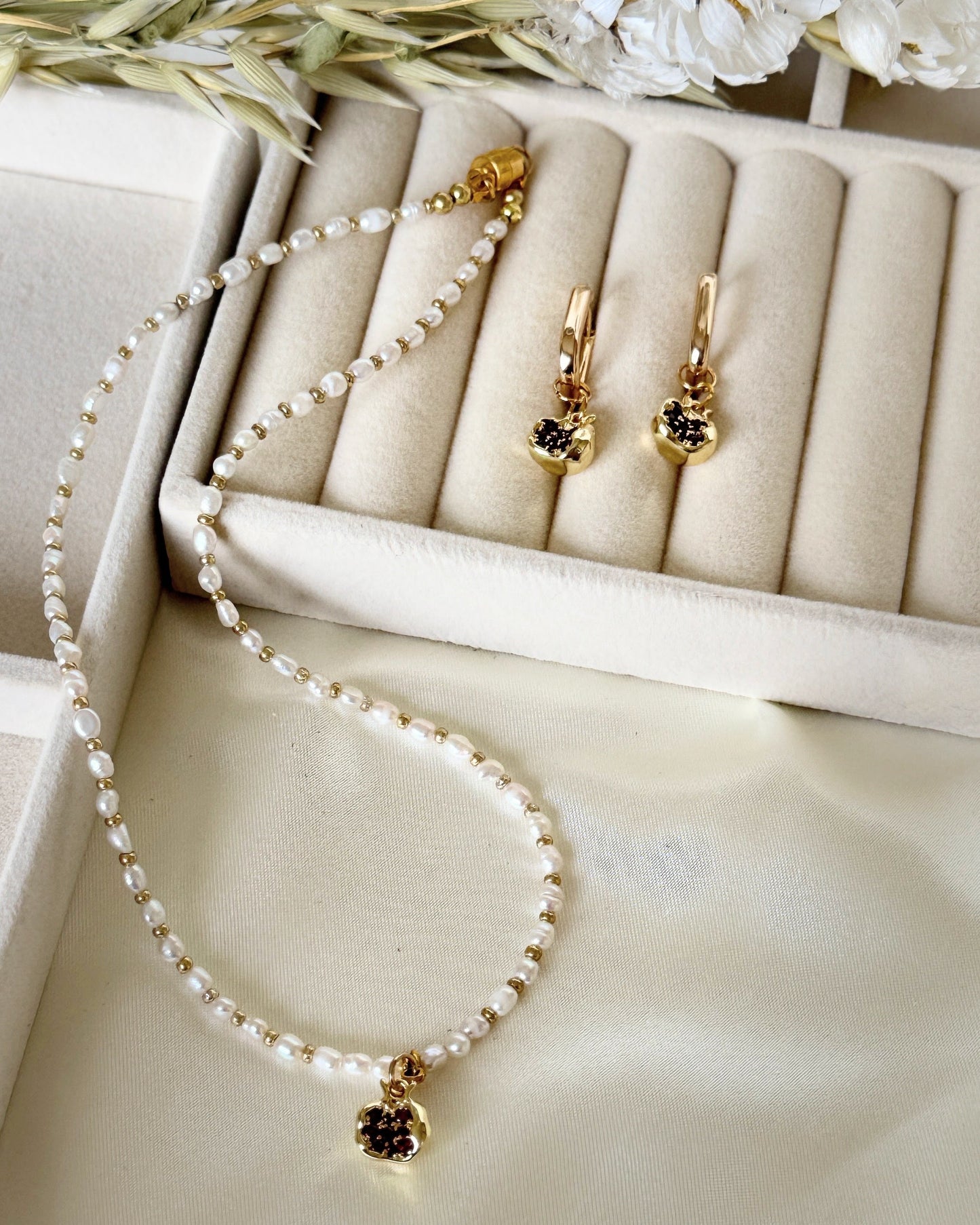 Golden pomegranate pearl necklace styled with jewelry accessories and decor