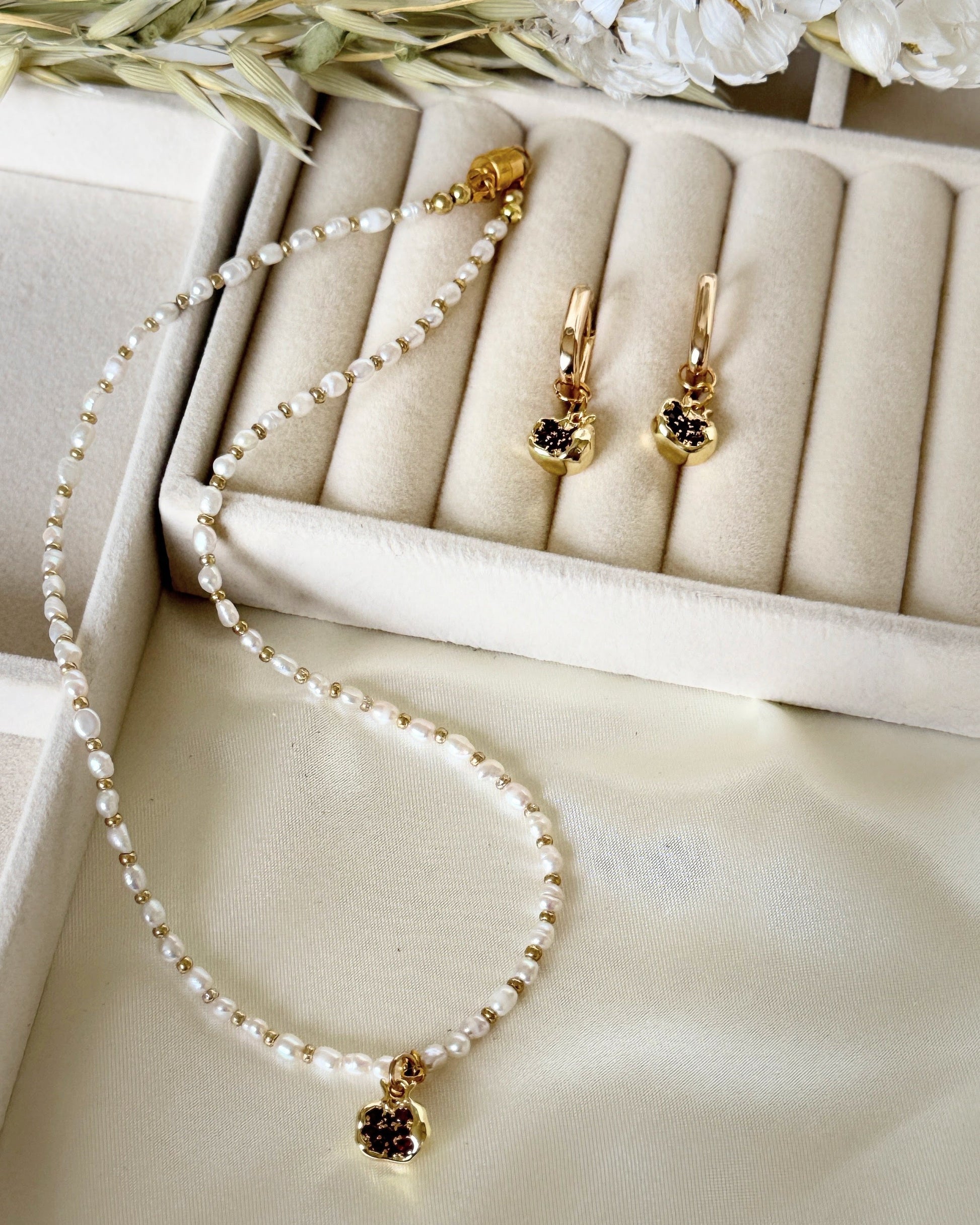 Golden pomegranate pearl necklace styled with jewelry accessories and decor