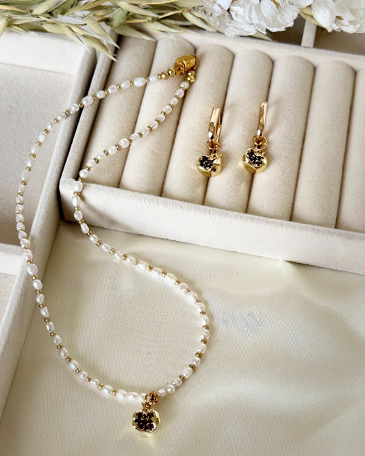 Golden pomegranate pearl necklace styled with jewelry accessories and decor