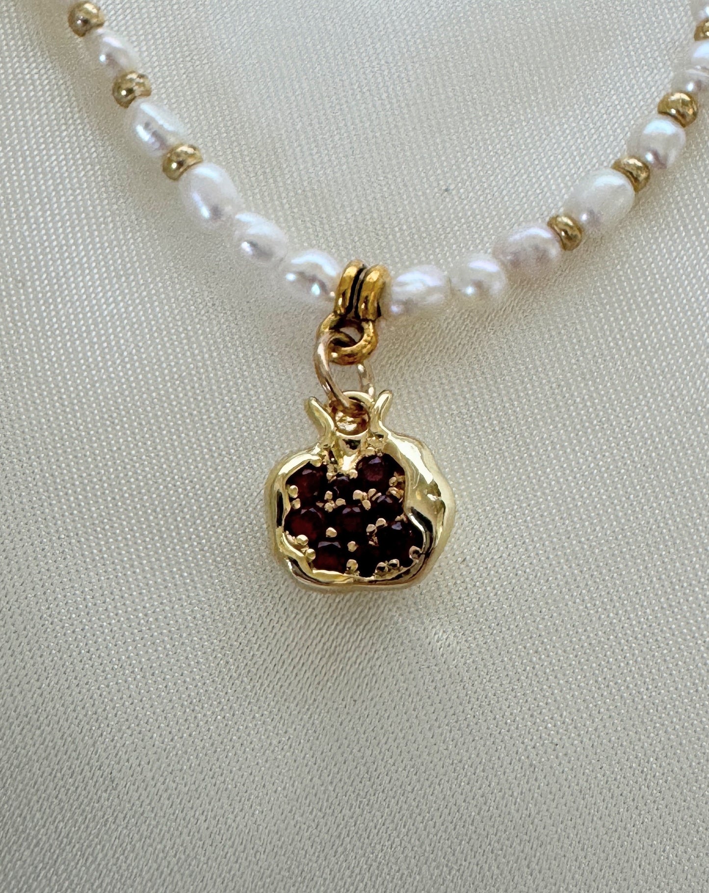 Golden pomegranate pearl necklace worn by woman with white blouse