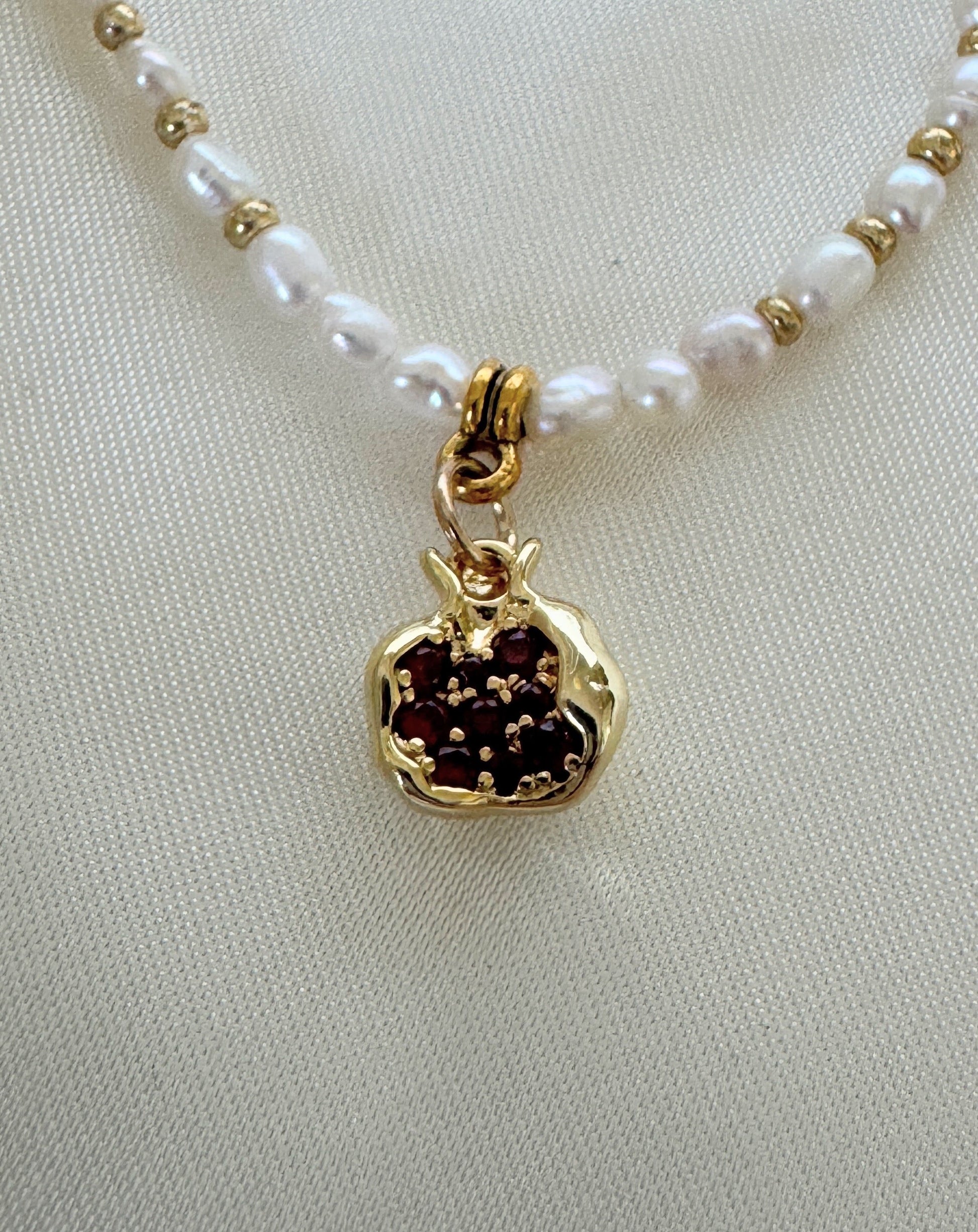 Golden pomegranate pearl necklace worn by woman with white blouse