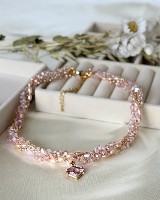 Pink layered crystal pearl necklace with gold accents on white background